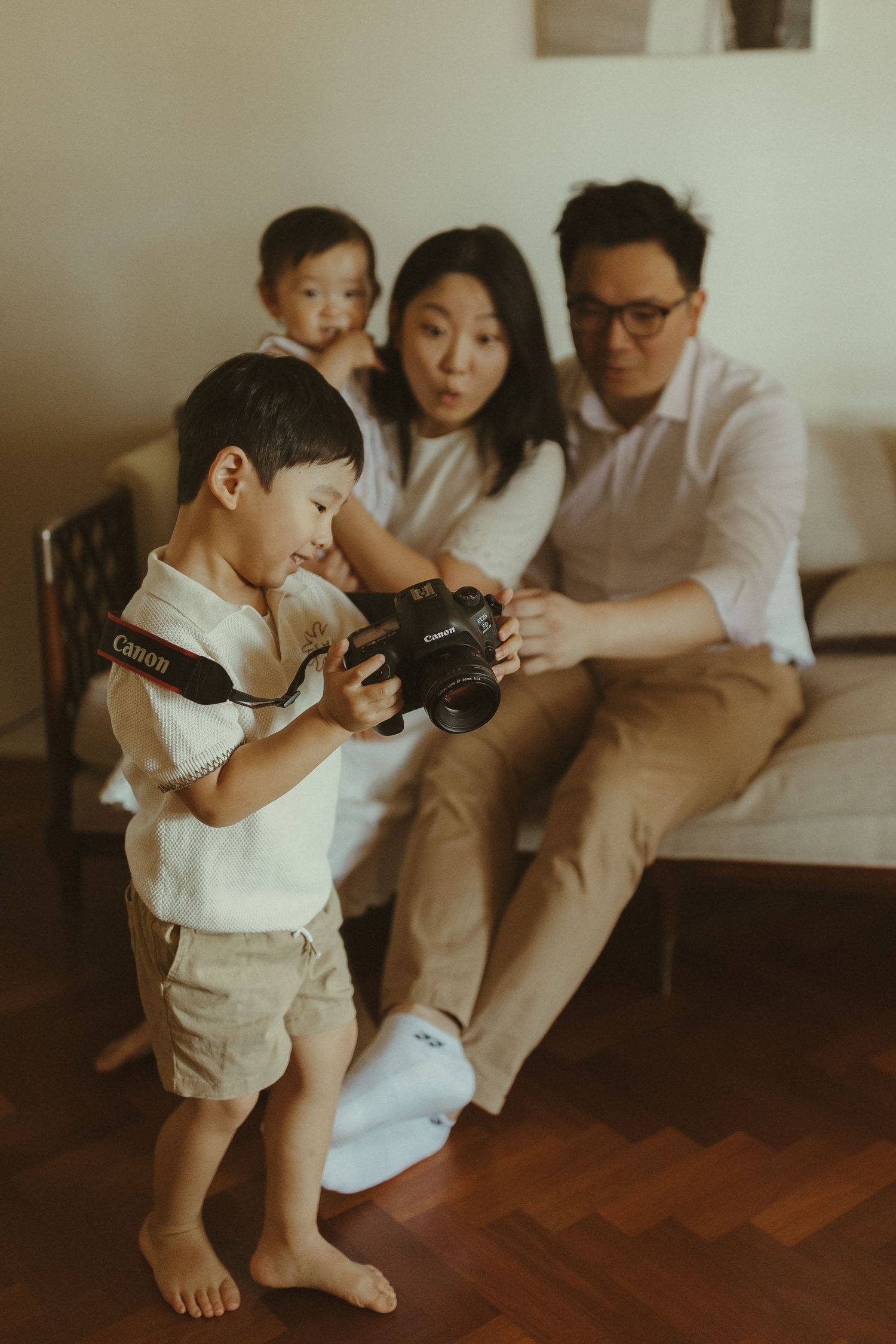 A family plays together on a wooden floor during a casual photoshoot.