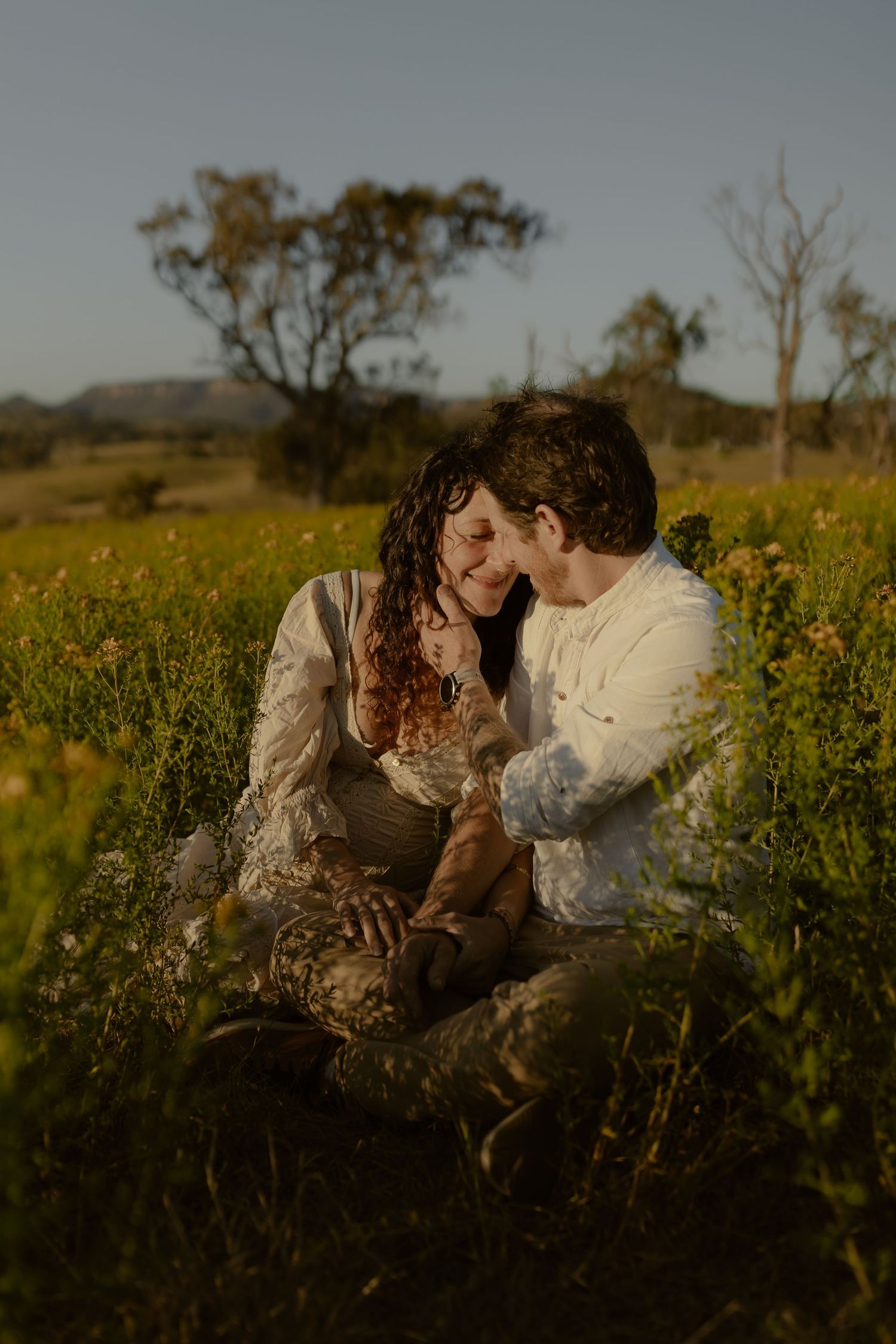A tender moment shared in a field of yellow flowers during sunset.