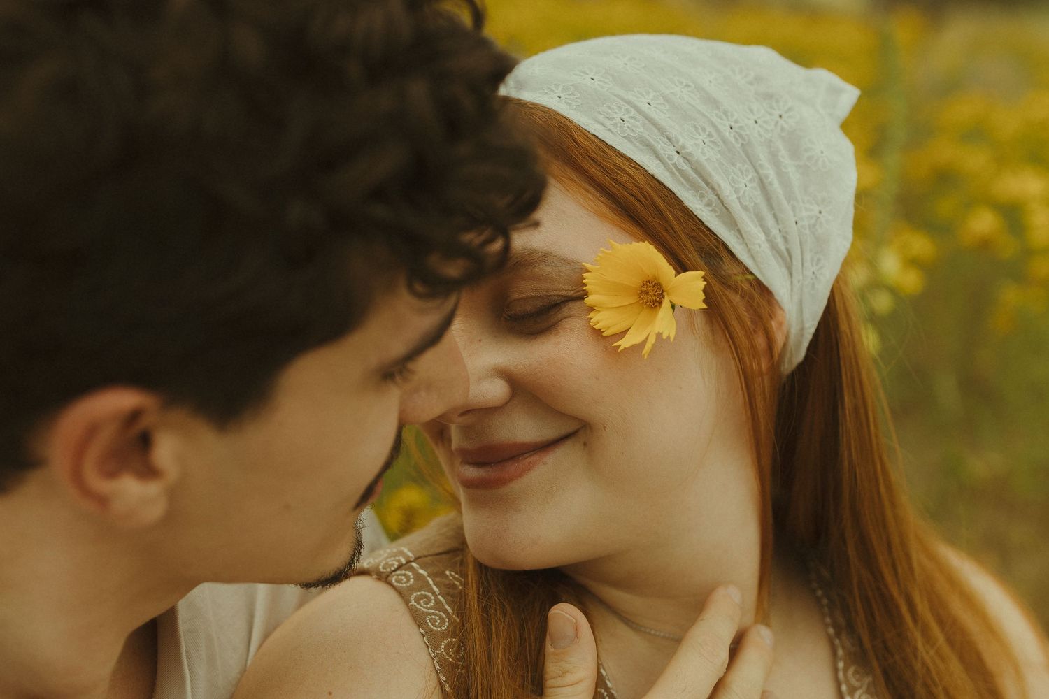 Romantic couple embraces in a golden sunlit meadow filled with yellow wildflowers on a warm autumn afternoon.
