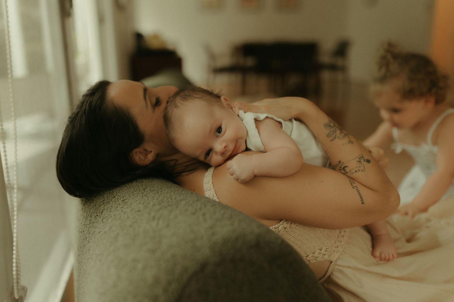A tender moment of rest and bonding on a cozy couch in soft window light.