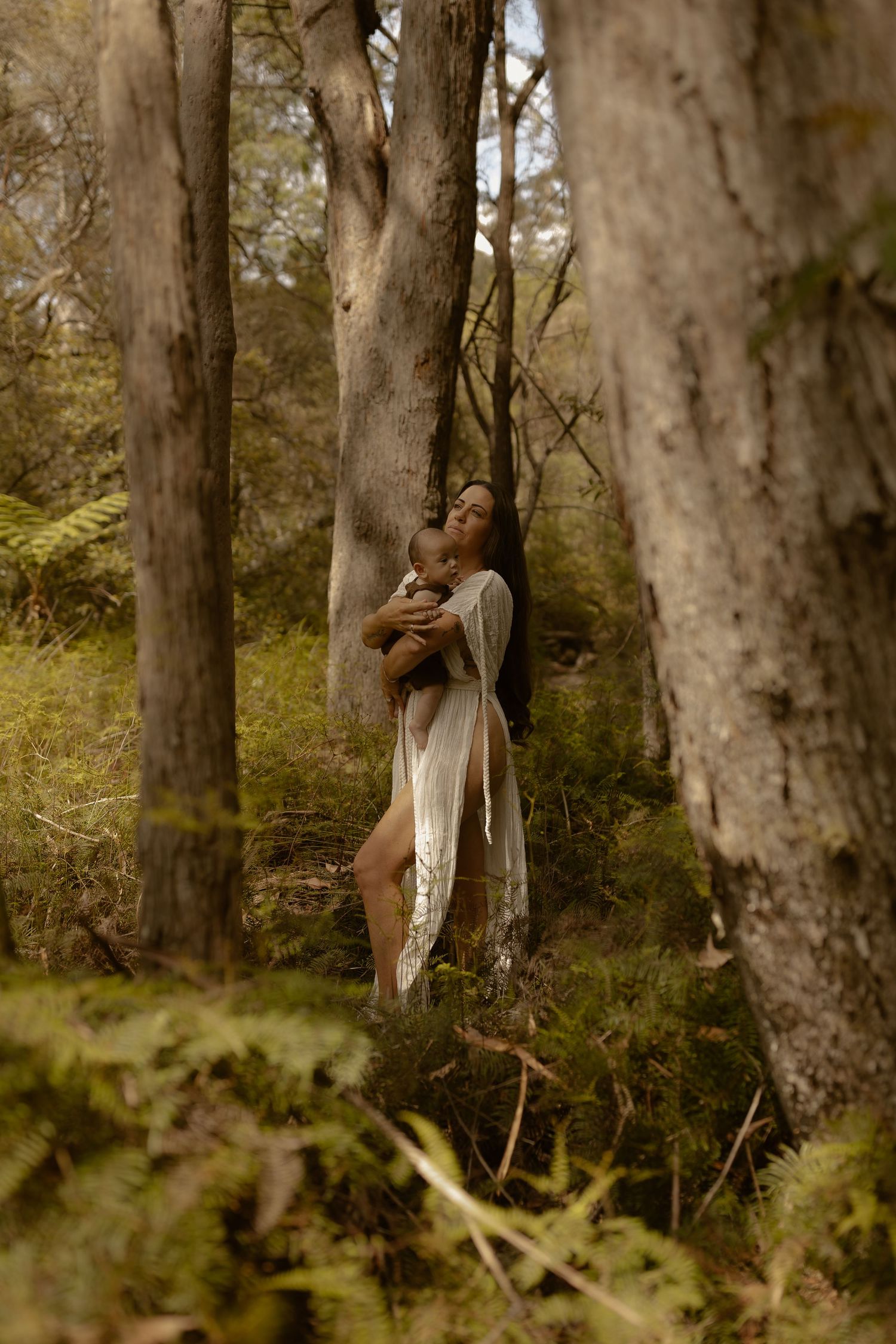 Artistic forest photoshoot with soft lighting and tall trees creating a dreamy woodland atmosphere.