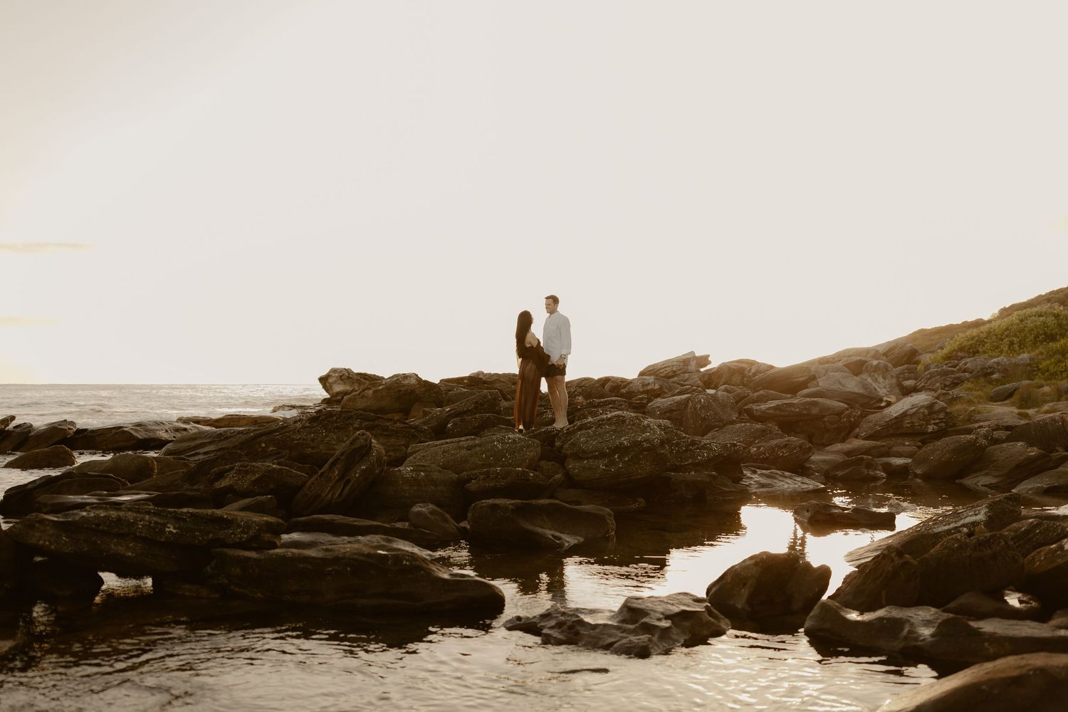 A series of vintage black and white photographs showing people on rocky coastal landscapes at sunset.