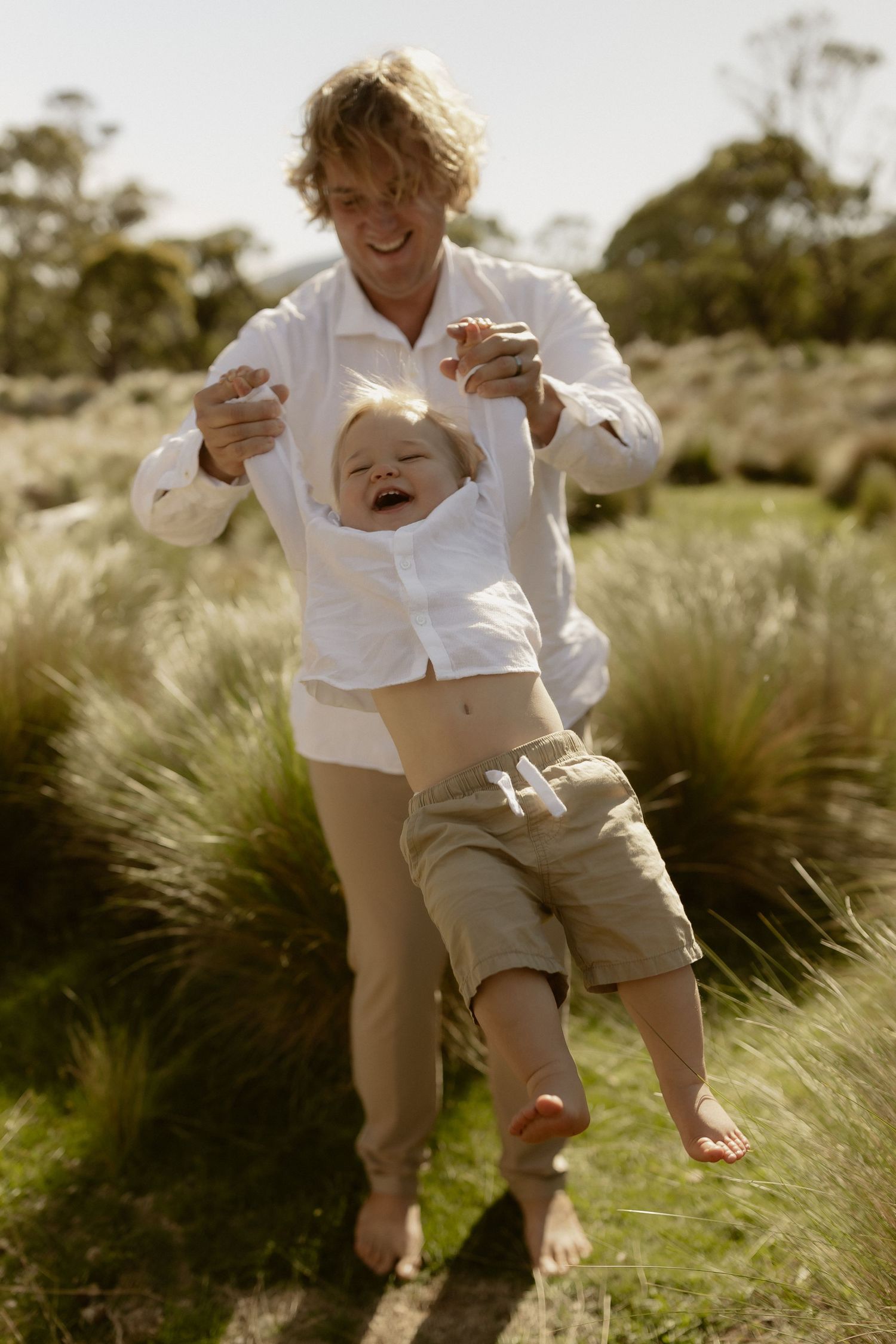 Candid sequence showing two people playing and laughing together in tall grass on a sunny afternoon.