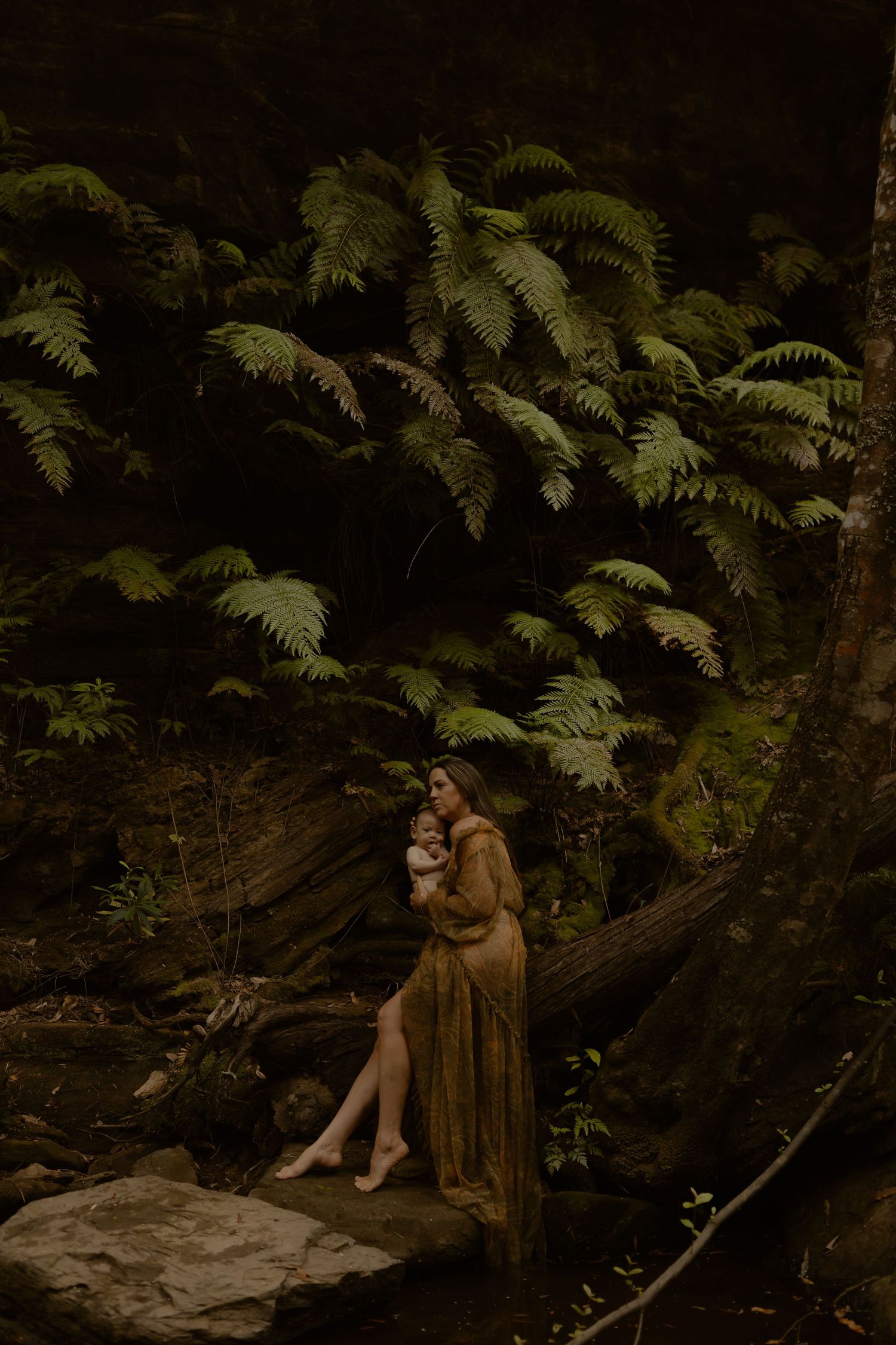Ethereal forest scene with mother and baby sitting on rock beneath towering ferns.