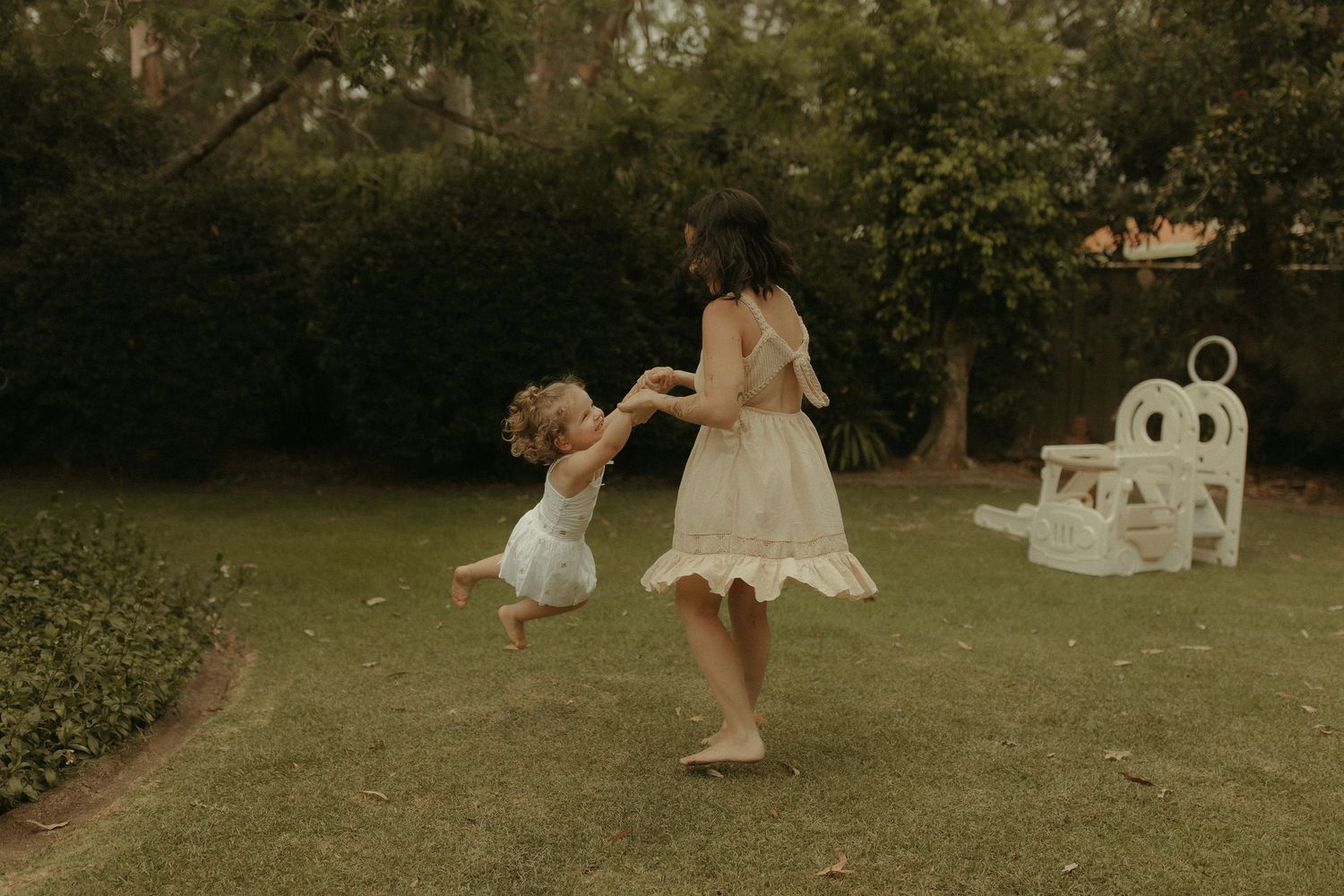 Candid outdoor family photography session in a lush green garden setting with soft natural lighting.