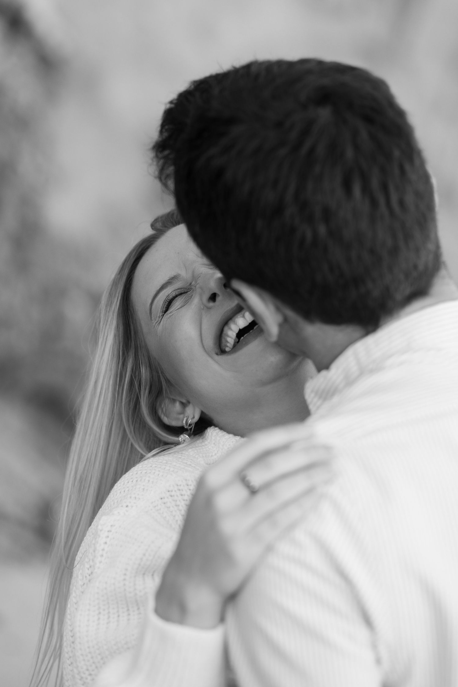 An intimate black and white portrait captures a couple sharing a tender laughing moment together.