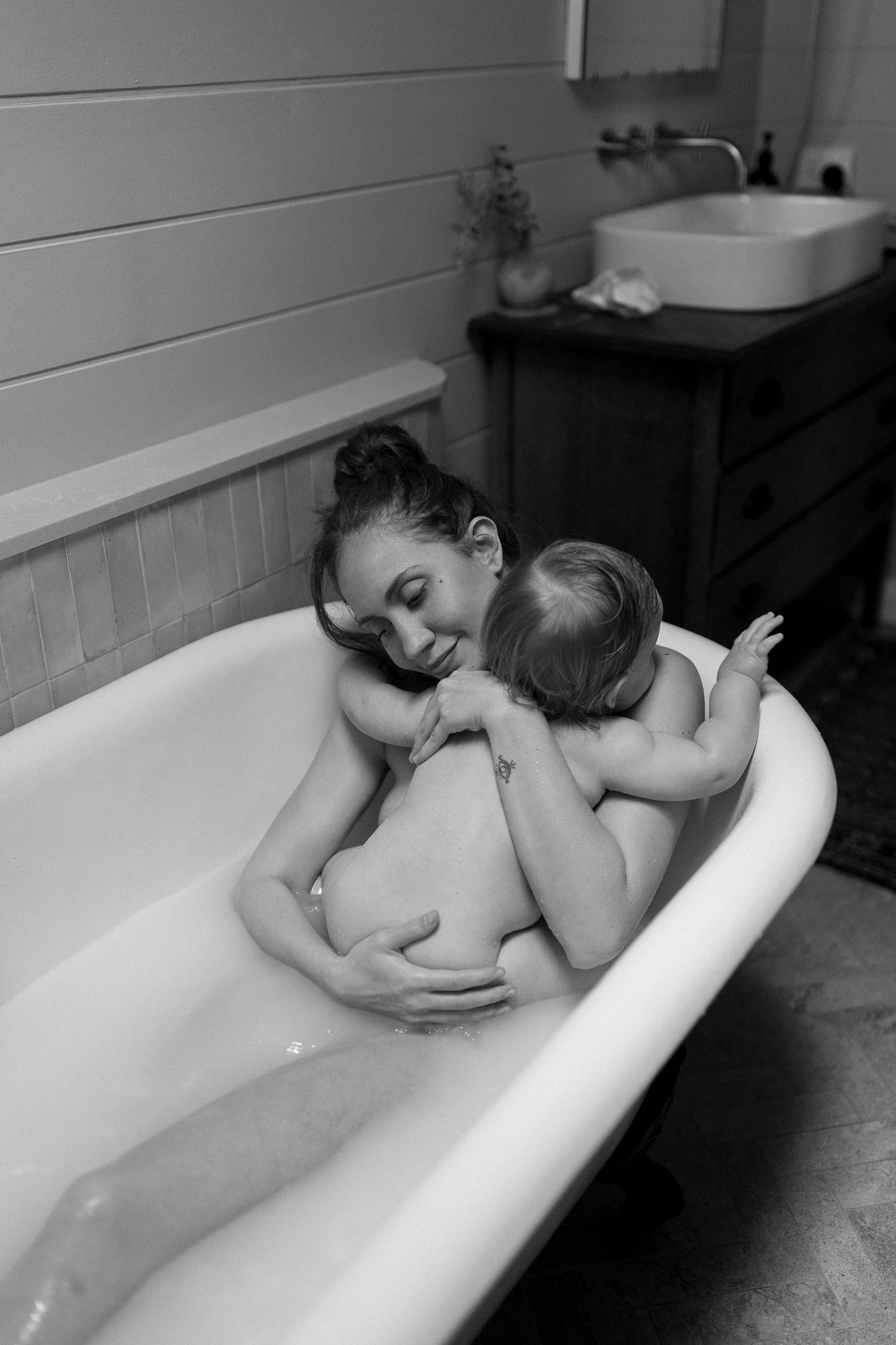 Intimate black and white bathing scene with soft natural lighting.