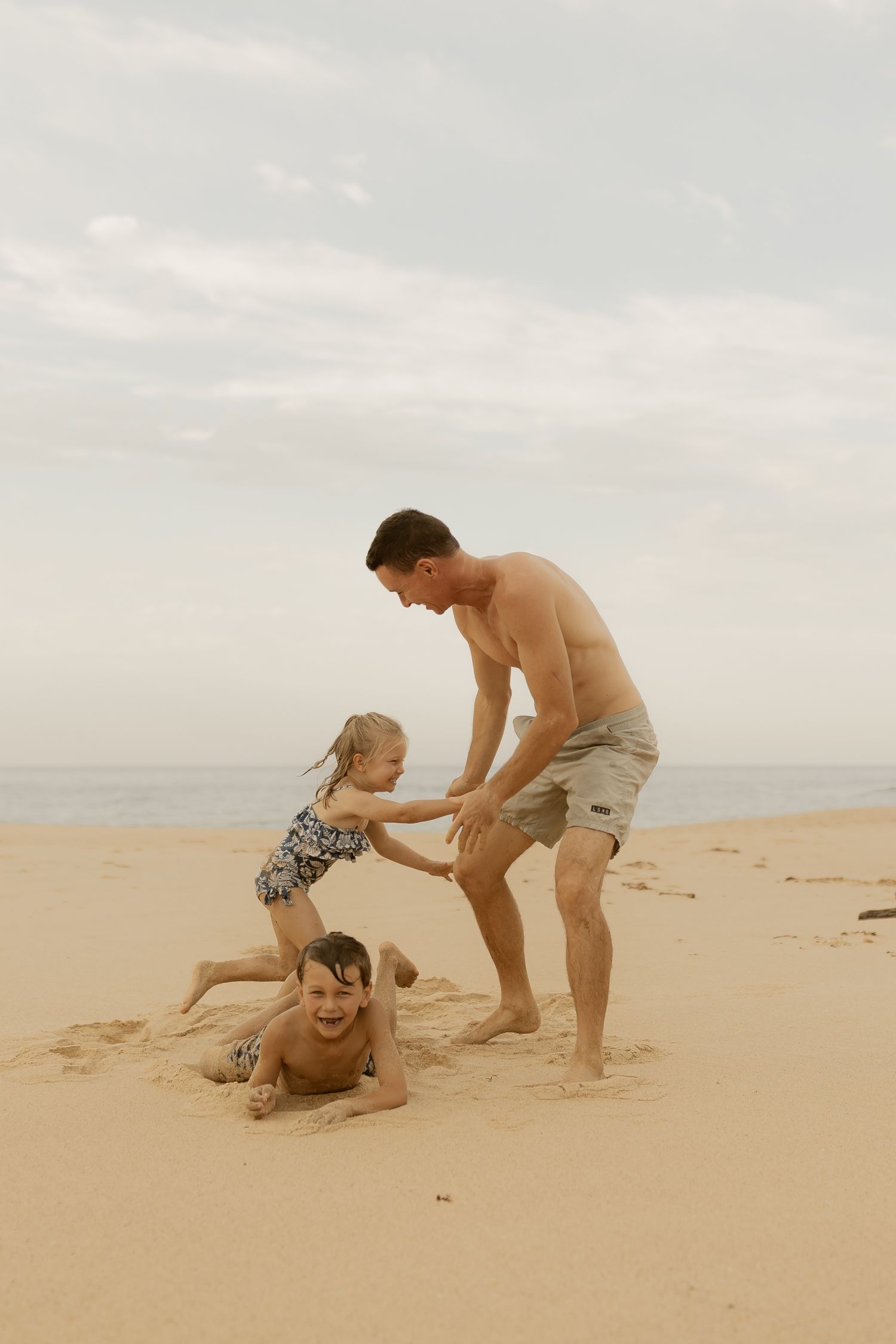 Two people playing and having fun on a sandy beach during sunset.