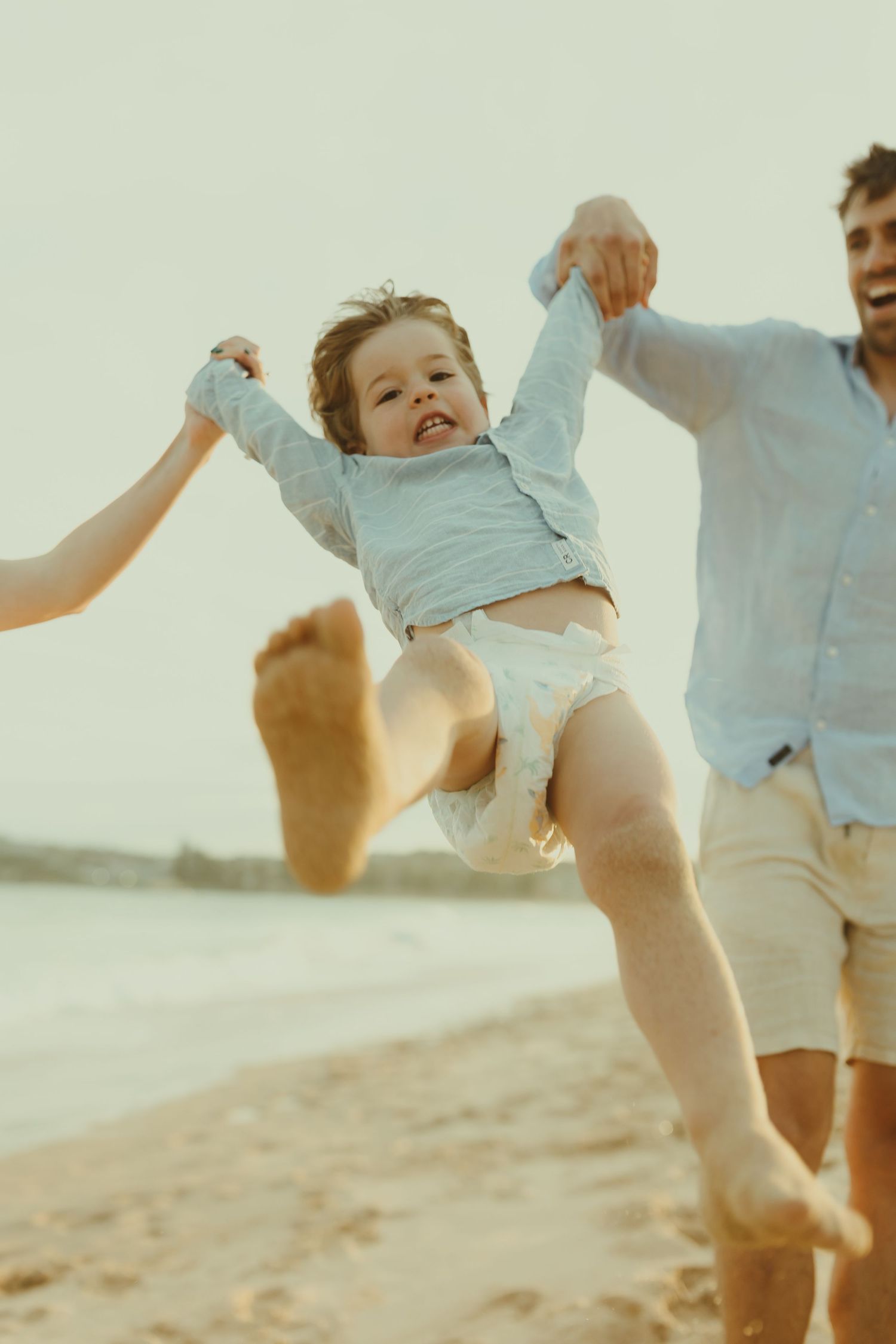 Child being lifted and spun on a beach during golden hour creating joyful action shots.