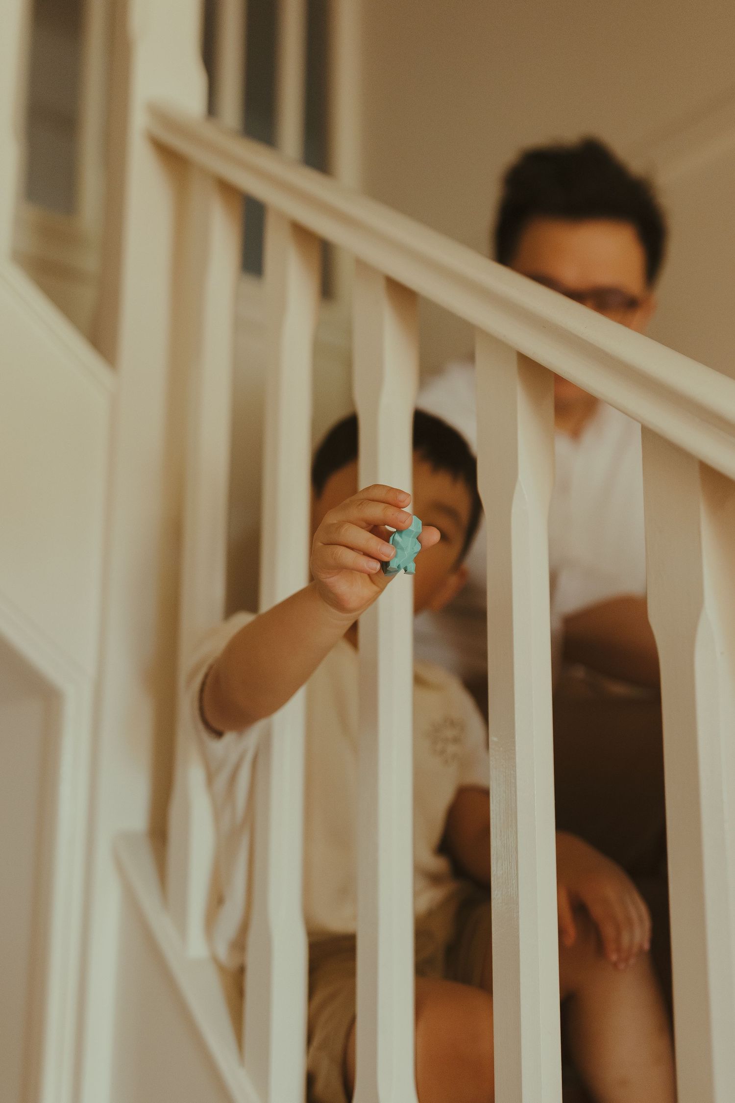 Candid moment captured through white stair railings in a home setting.
