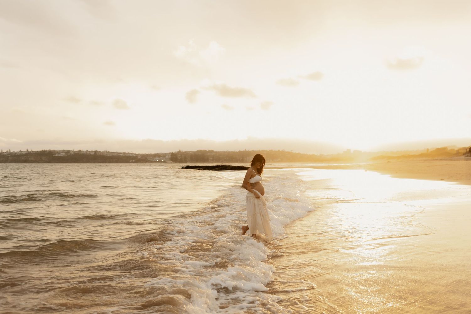 A silhouette dances on a beach at sunset as golden light reflects off the ocean waves.