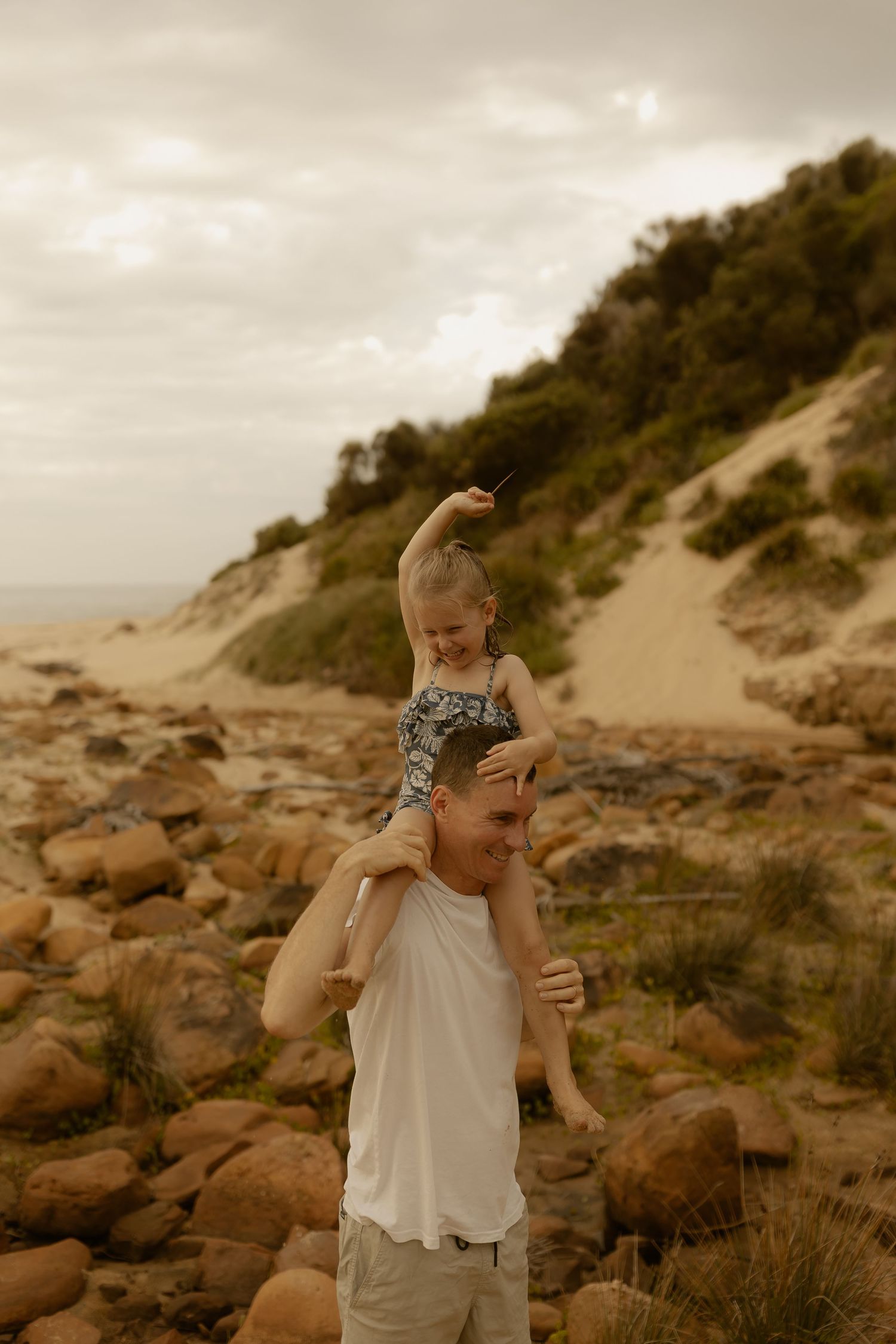 Family enjoying a tender moment together among coastal sand dunes at golden hour.