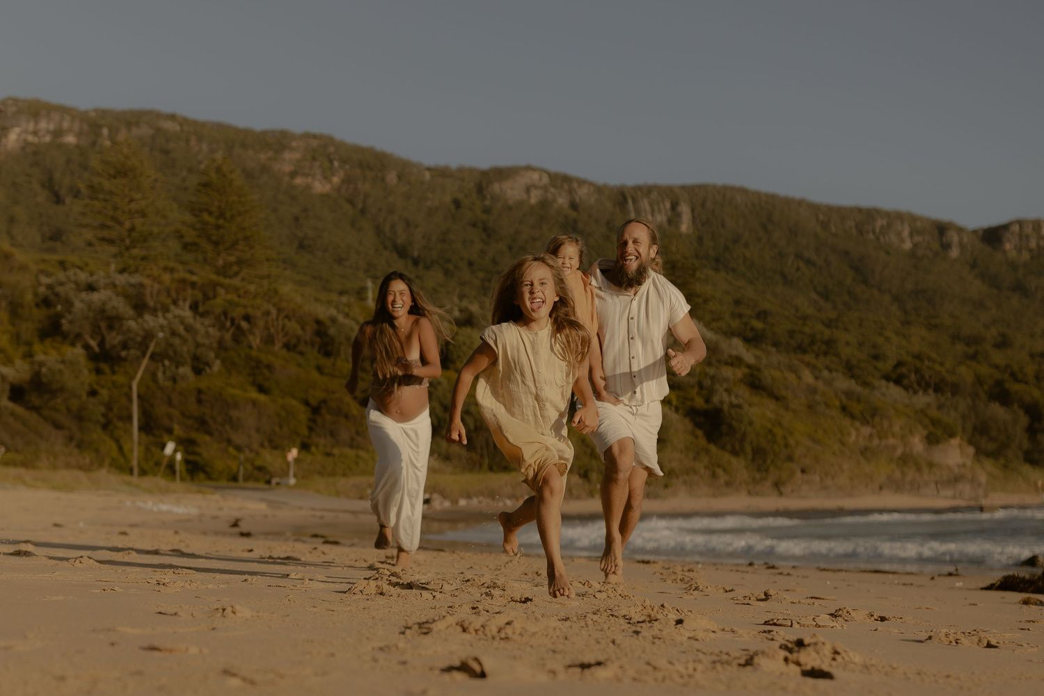 Group walking along a scenic beach path with cliffs and golden sunlight in the background.
