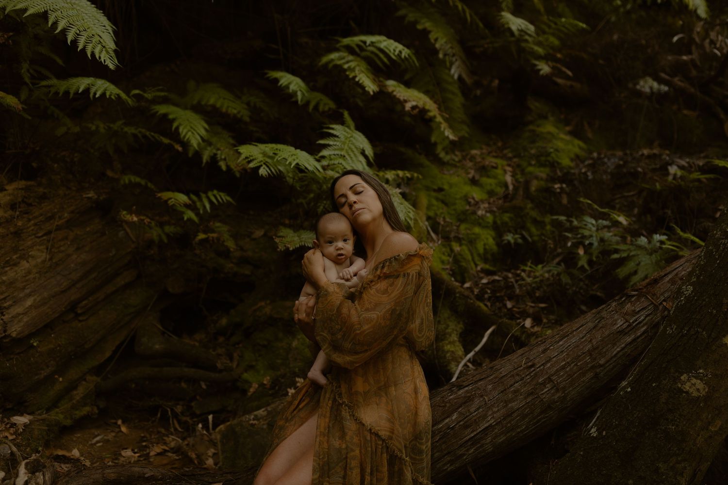 A romantic couple shares tender moments in a lush forest setting during a golden hour photoshoot.