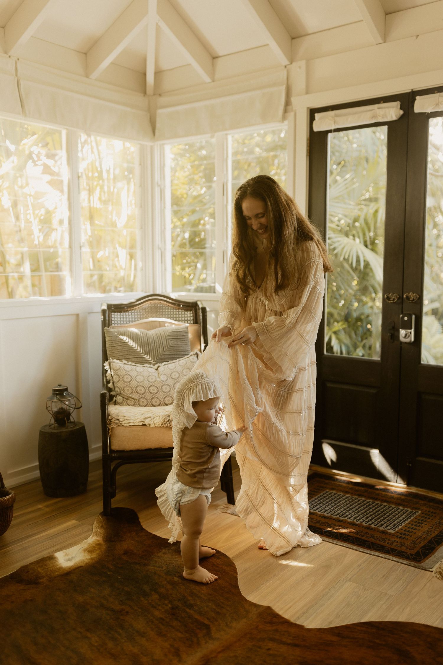 Dancing figure in white dress twirls through sunlit room with wooden floors.