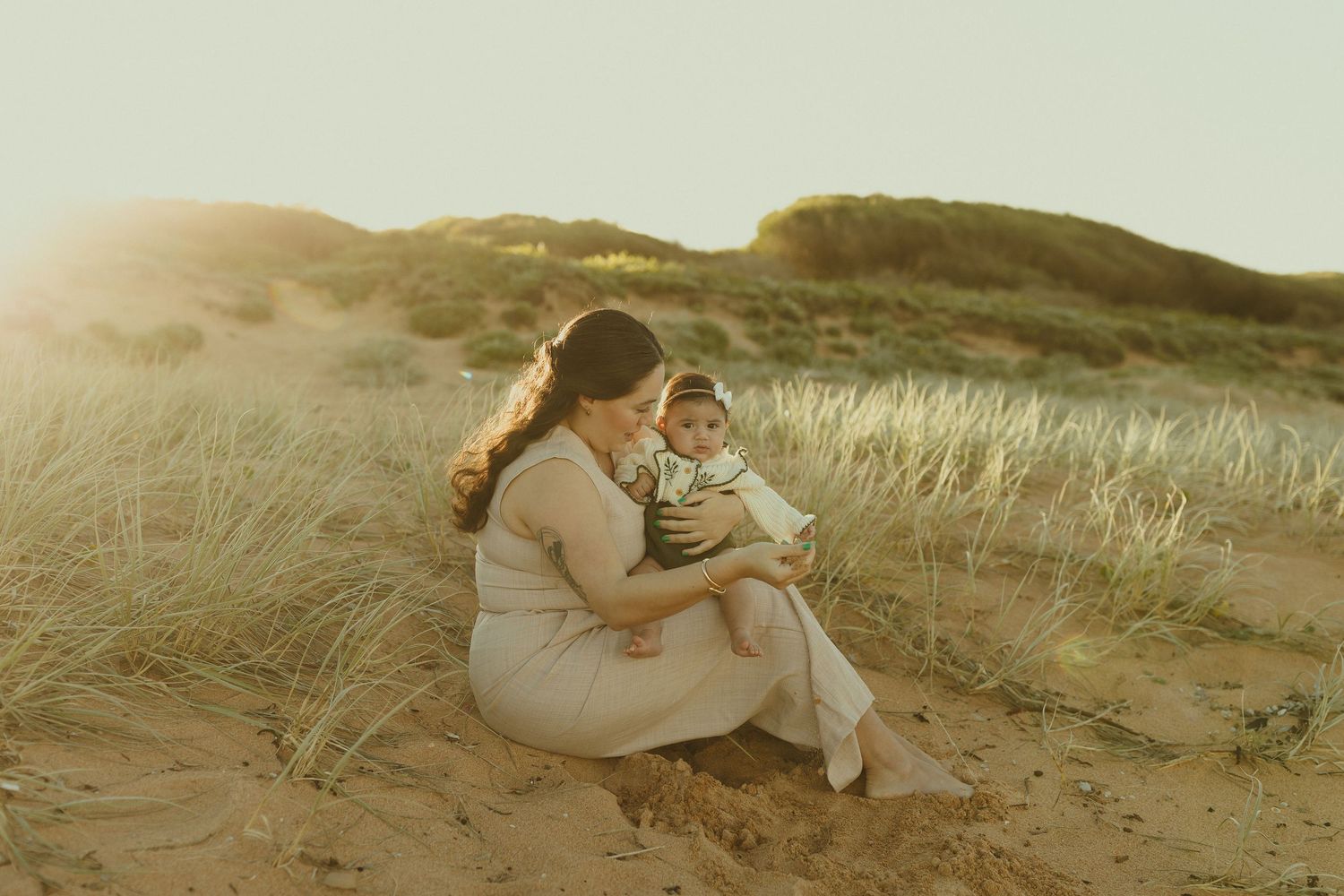 A series of romantic photos of a couple embracing in rolling sand dunes and tall grass during golden hour.