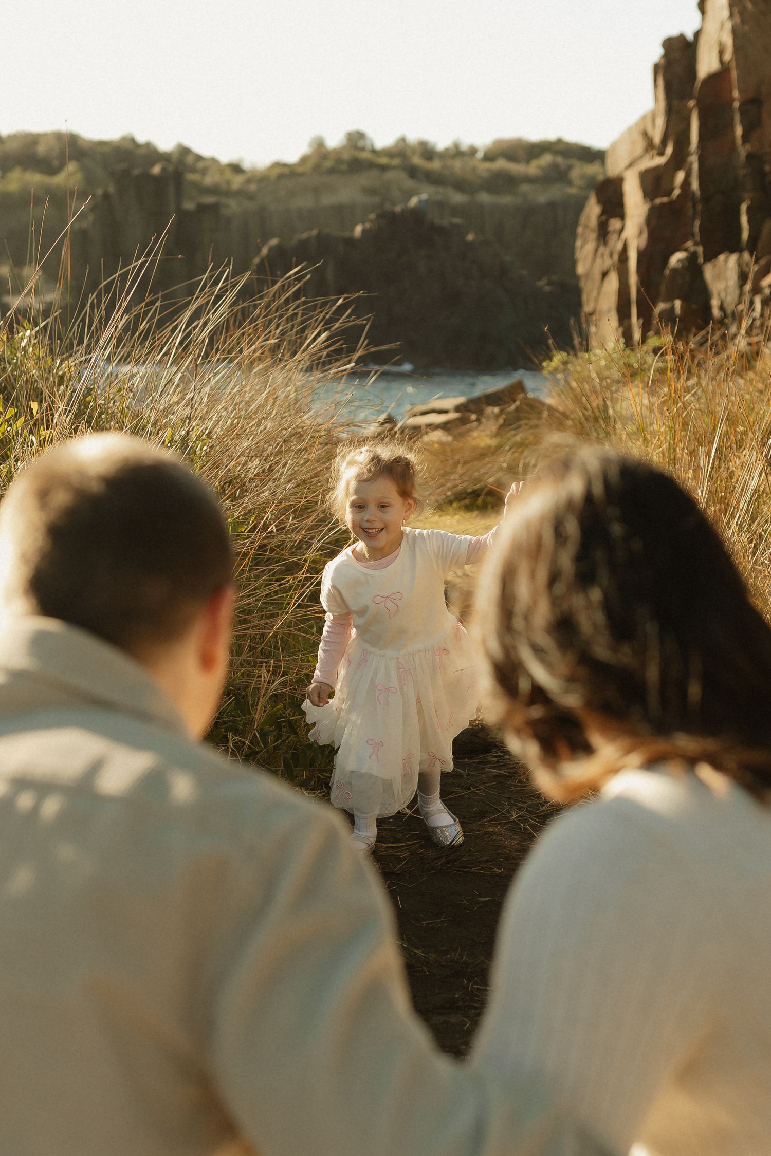 Heartwarming family scene captured against dramatic coastal cliffs during golden hour.
