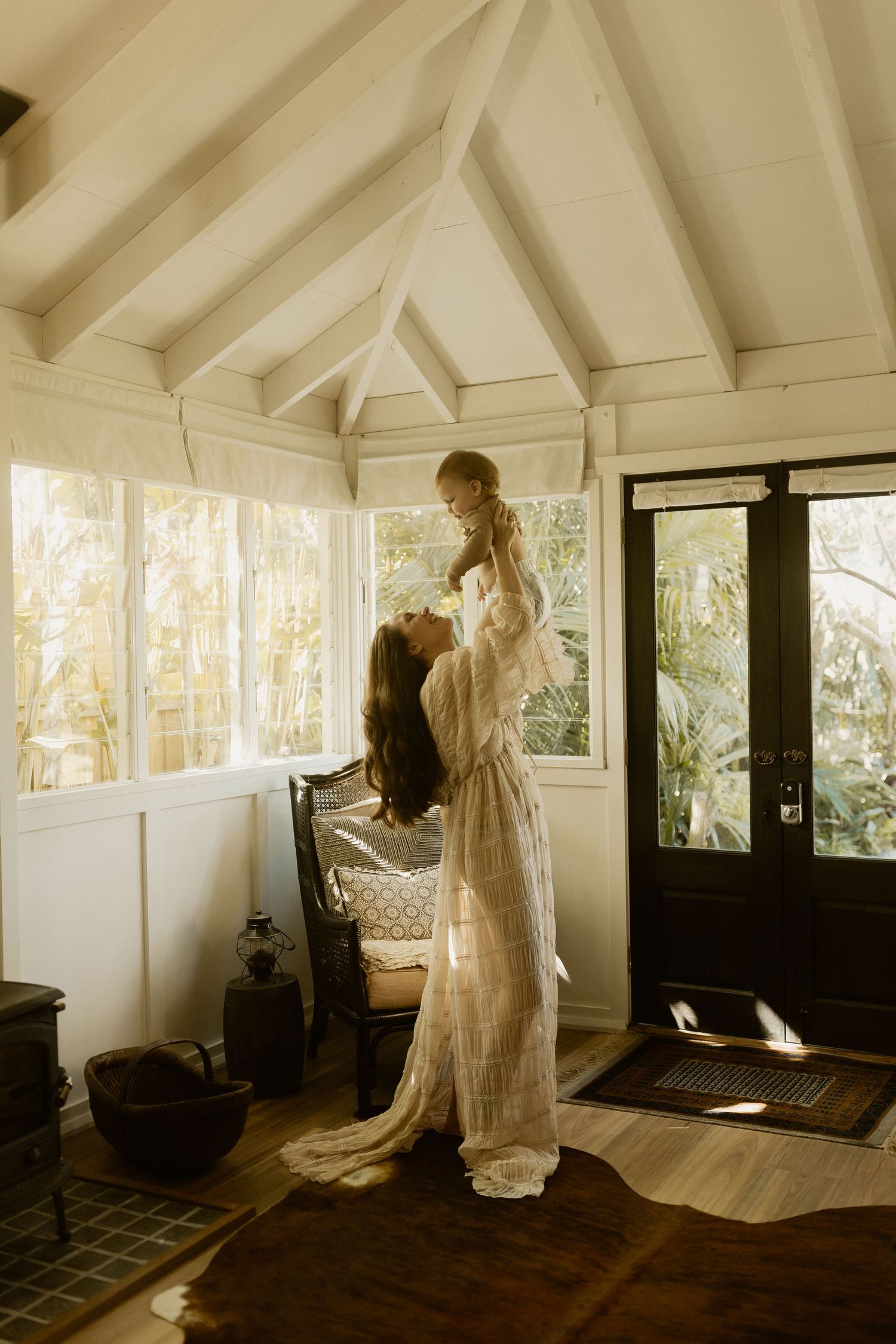 A sunlit room with vaulted ceilings shows two people sharing an intimate moment in flowing white clothing.