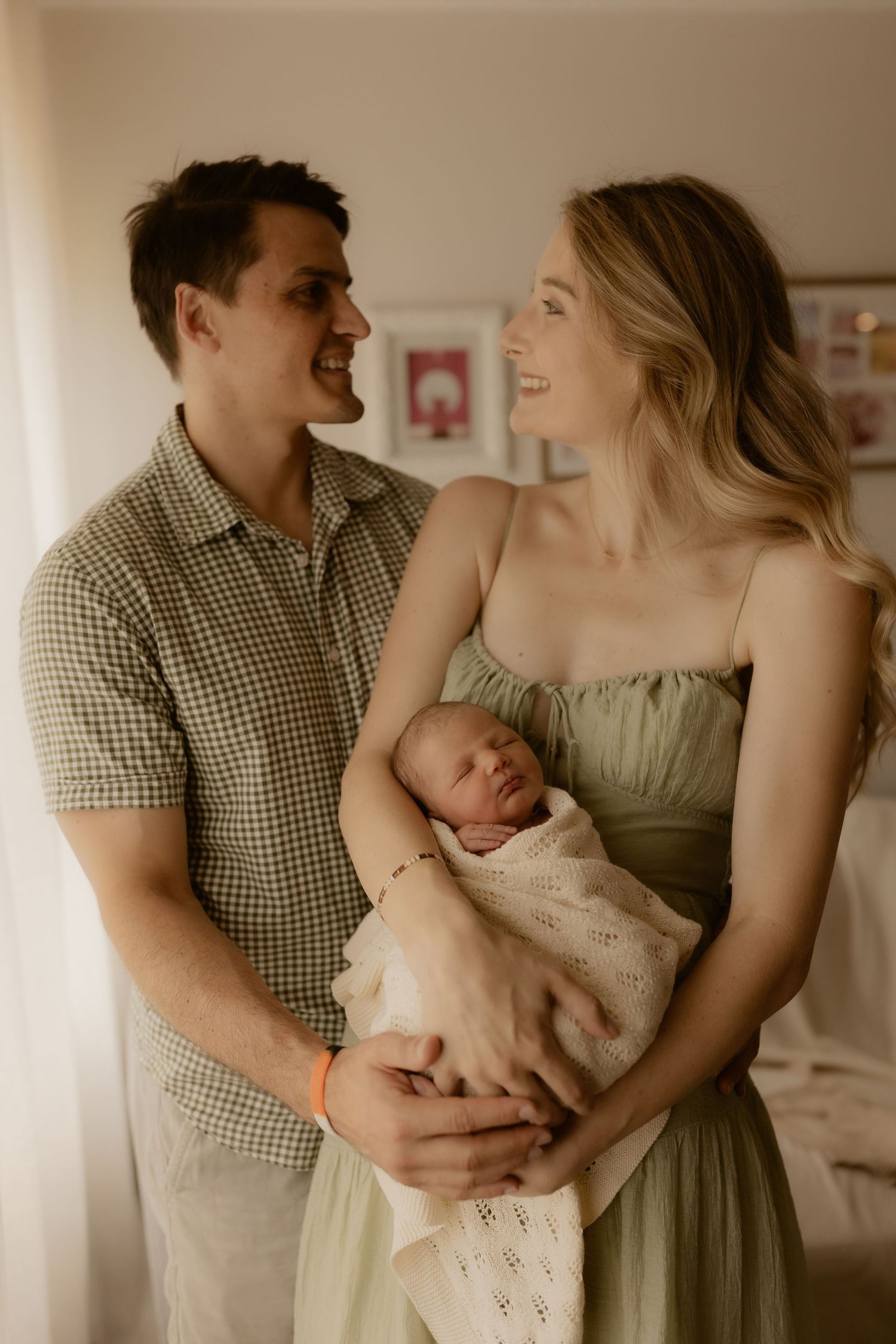 Family portrait series showing tender moments with newborn baby in sage green and gingham outfits.