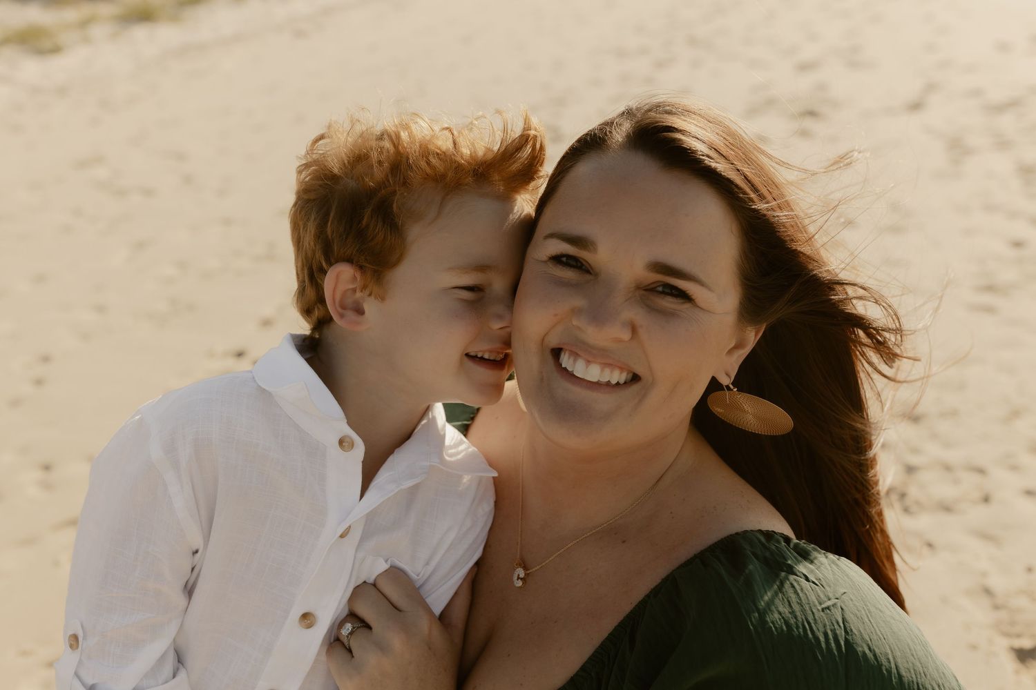 Family enjoying a playful moment together on a sunny beach with natural lighting.