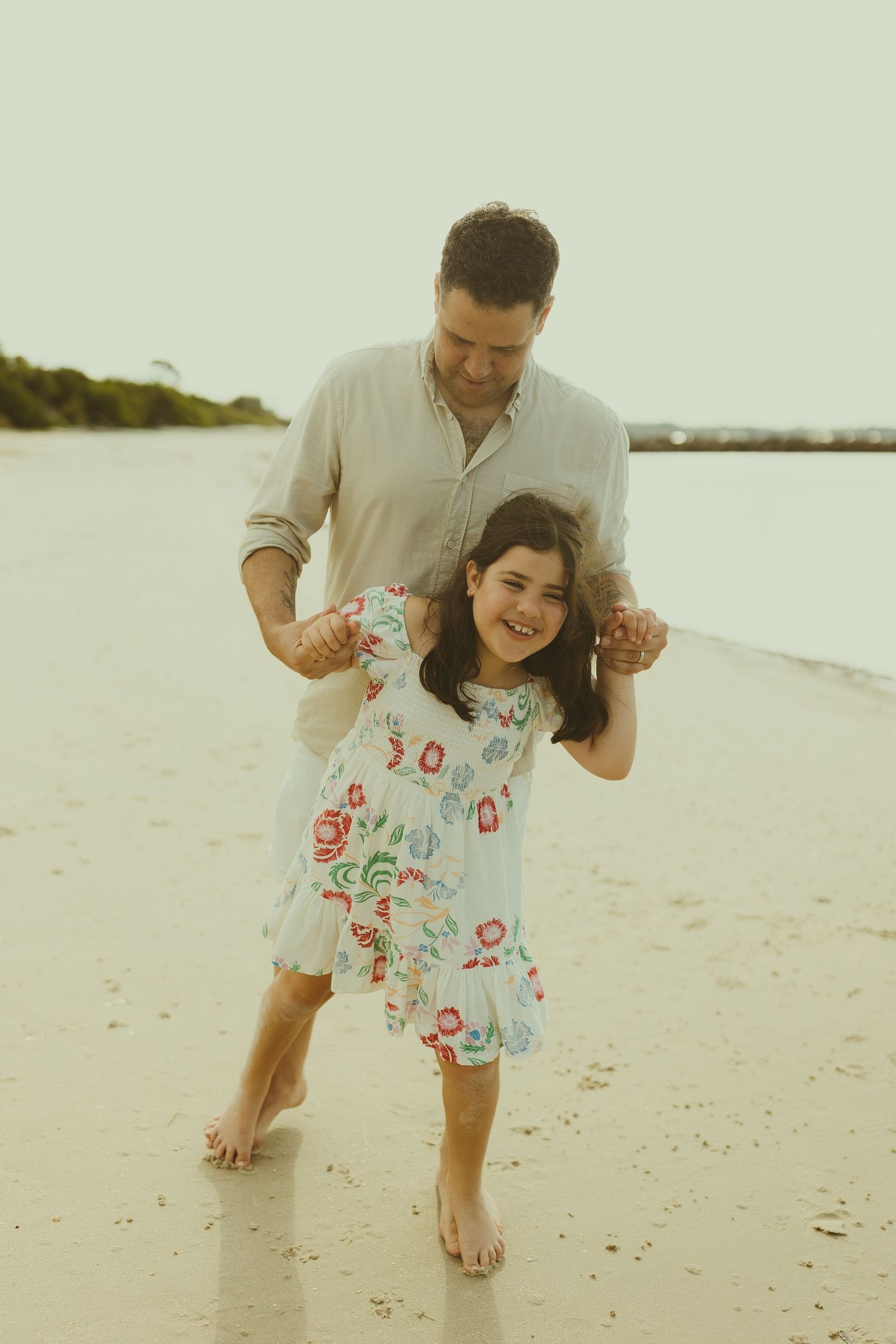 Playful scene of family members enjoying a fun moment together on a sandy beach.