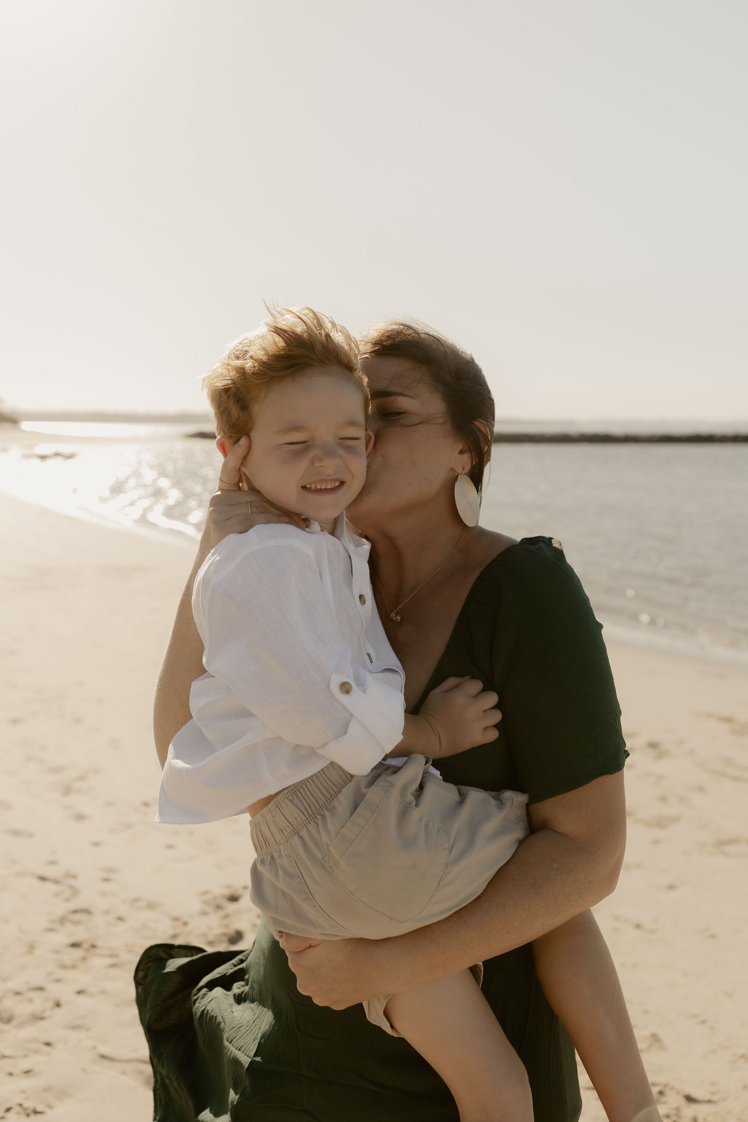 A tender moment shared between parent and child on a sunny beach, captured in a series of candid photographs.