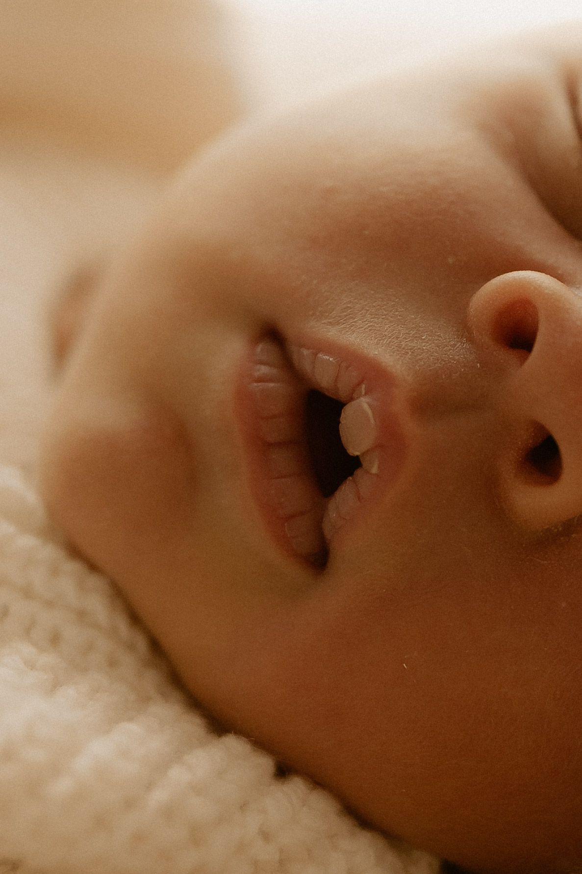 Close-up view of a sleeping baby's nose and mouth showing peaceful rest on soft white bedding.