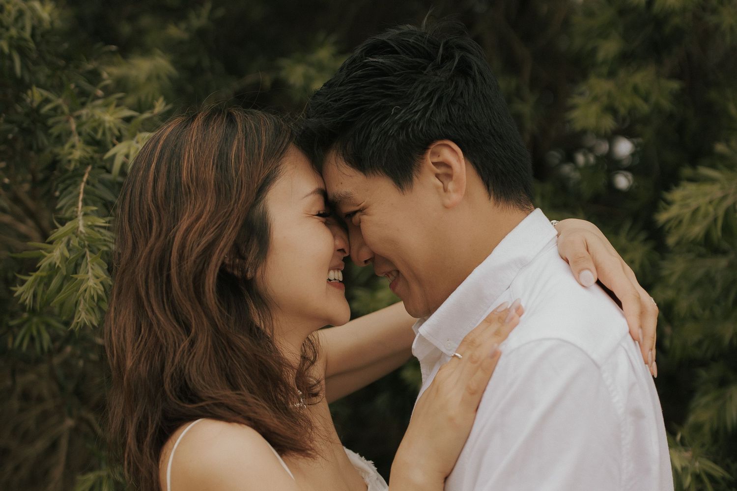 A romantic couple shares tender moments in a lush garden setting during their engagement photo session.