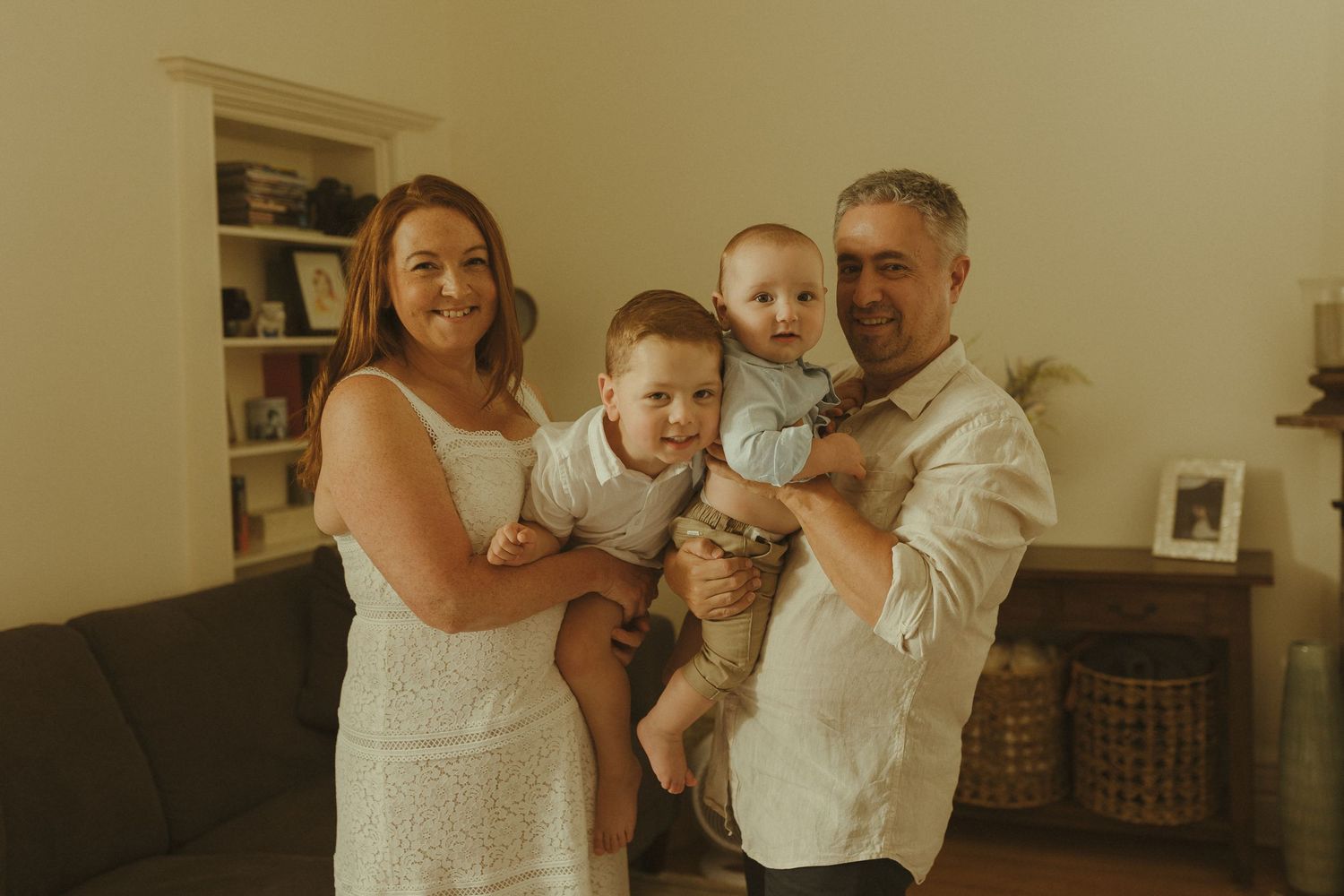 Family spending quality time together indoors with a baby and toys visible in the background.