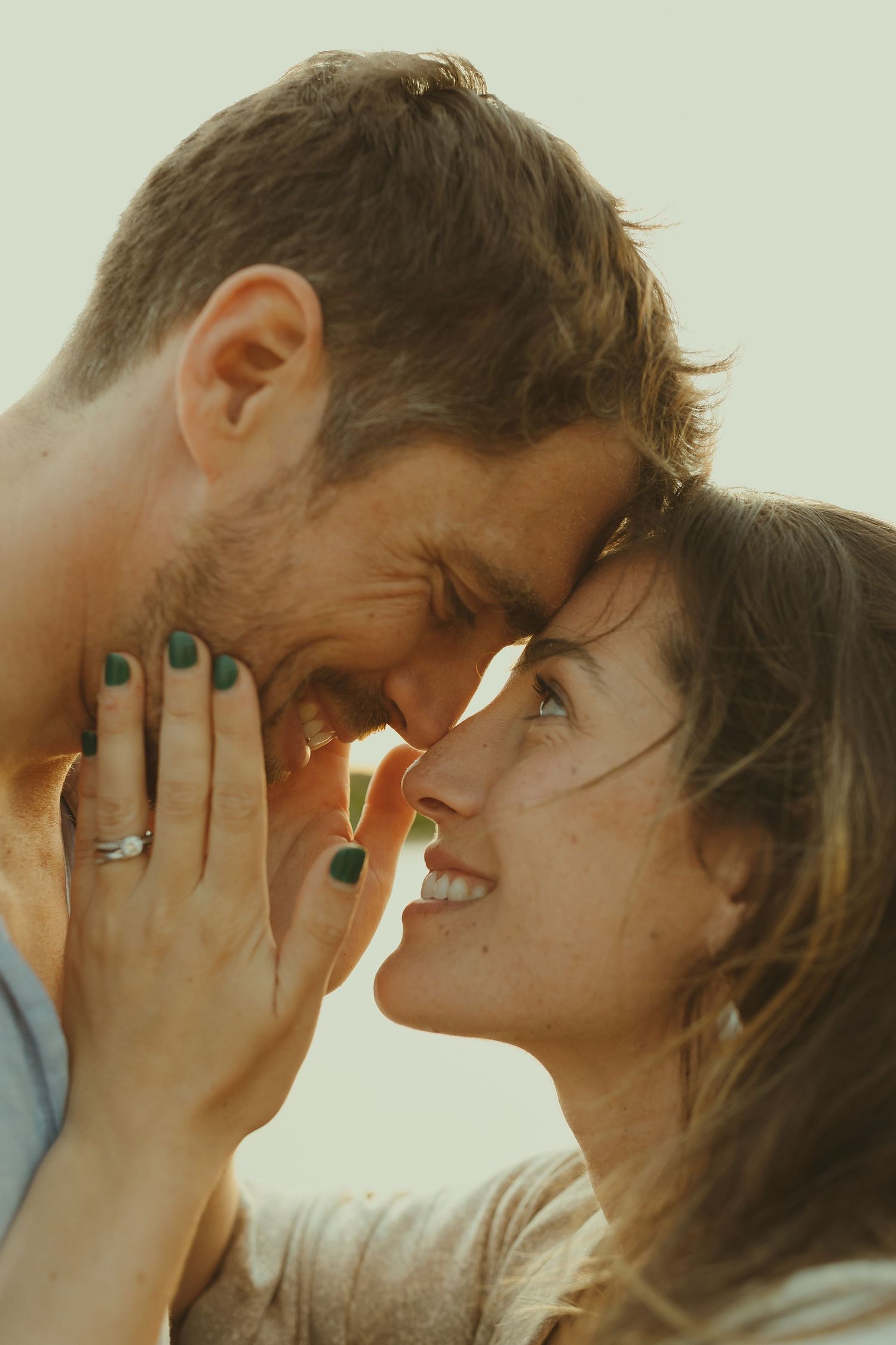 Intimate romantic moment between couple sharing laughter in warm sunlit close-up.
