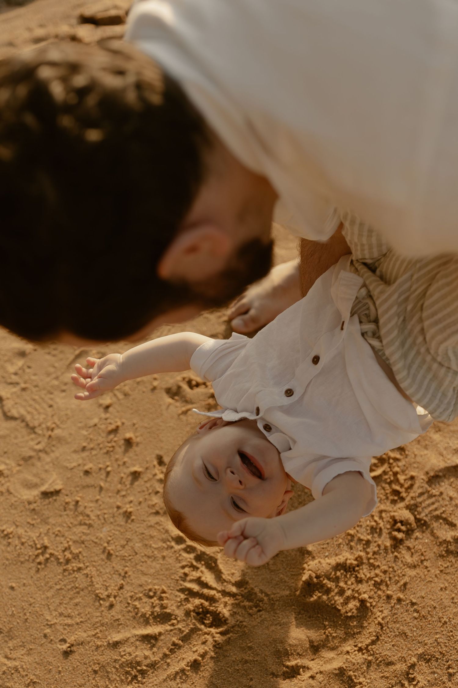 Baby playing in the sand during golden hour at the beach.