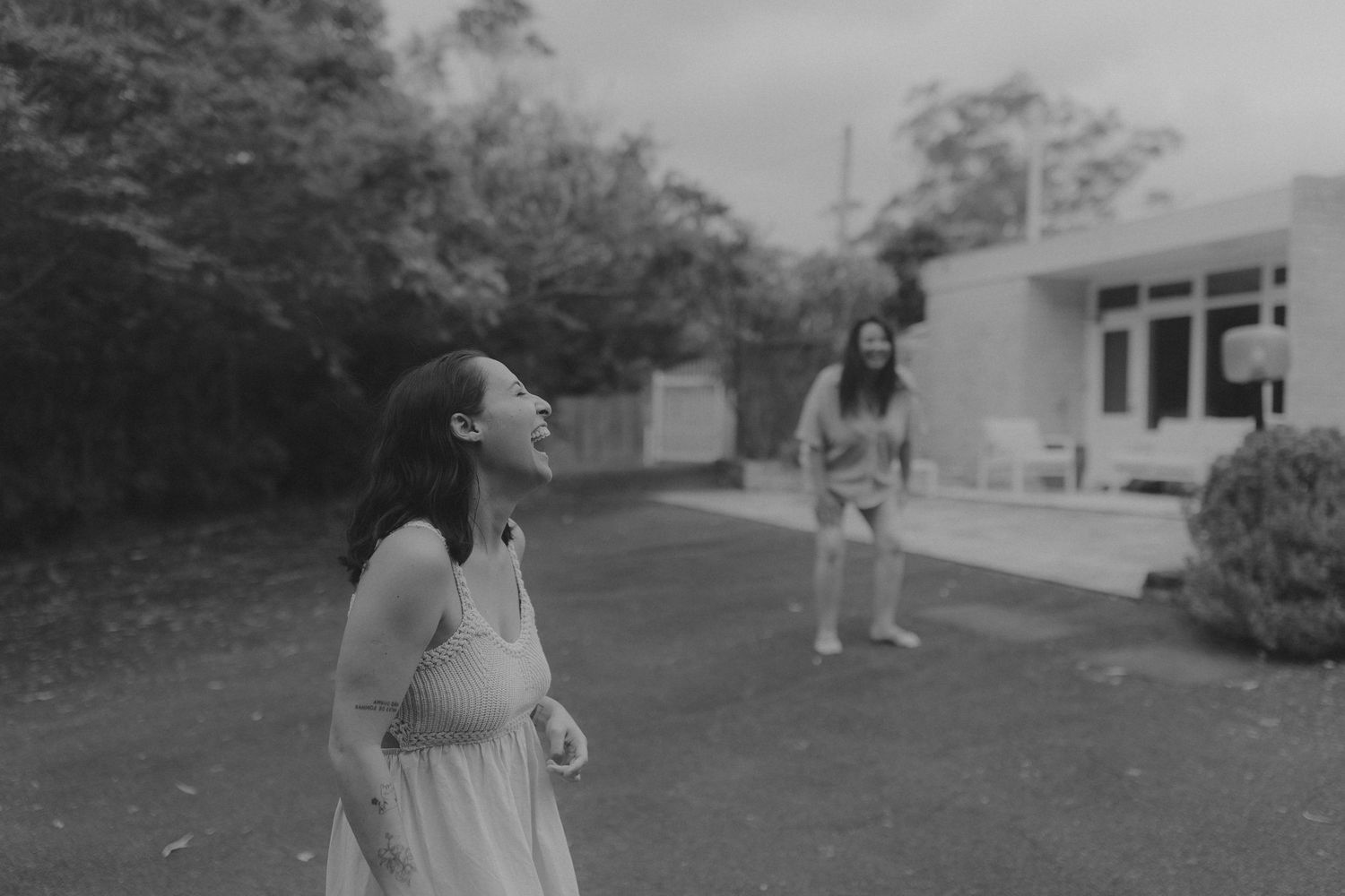 A black and white photograph capturing a playful moment in a backyard setting.