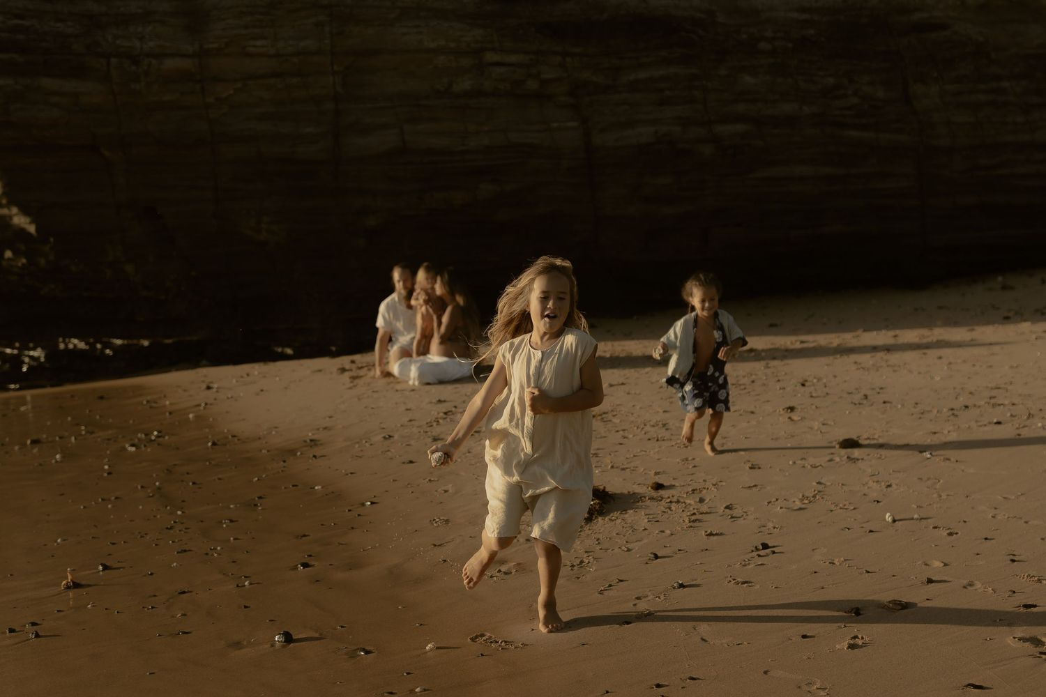 Children playing and running along shoreline during golden hour beach photography session.