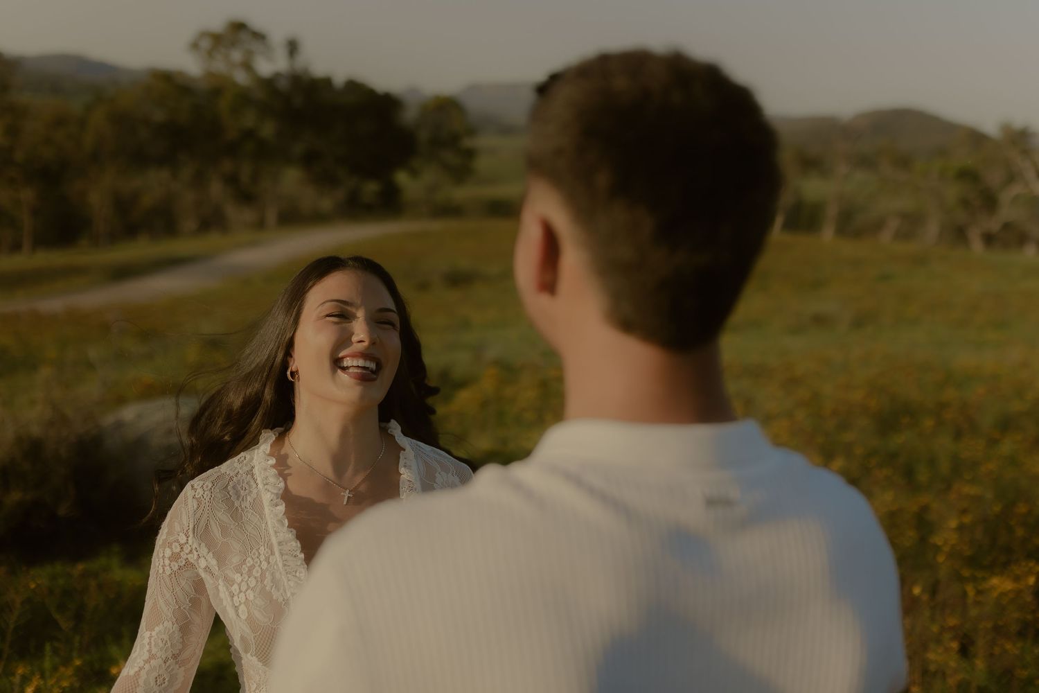 Intimate moment captured between a couple laughing together in a sunny field.