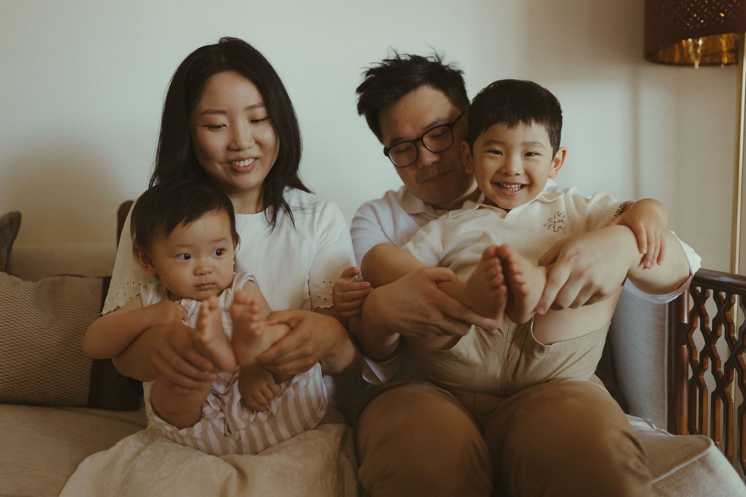 Family members share joyful moments together while sitting on a couch in a warmly lit living room.