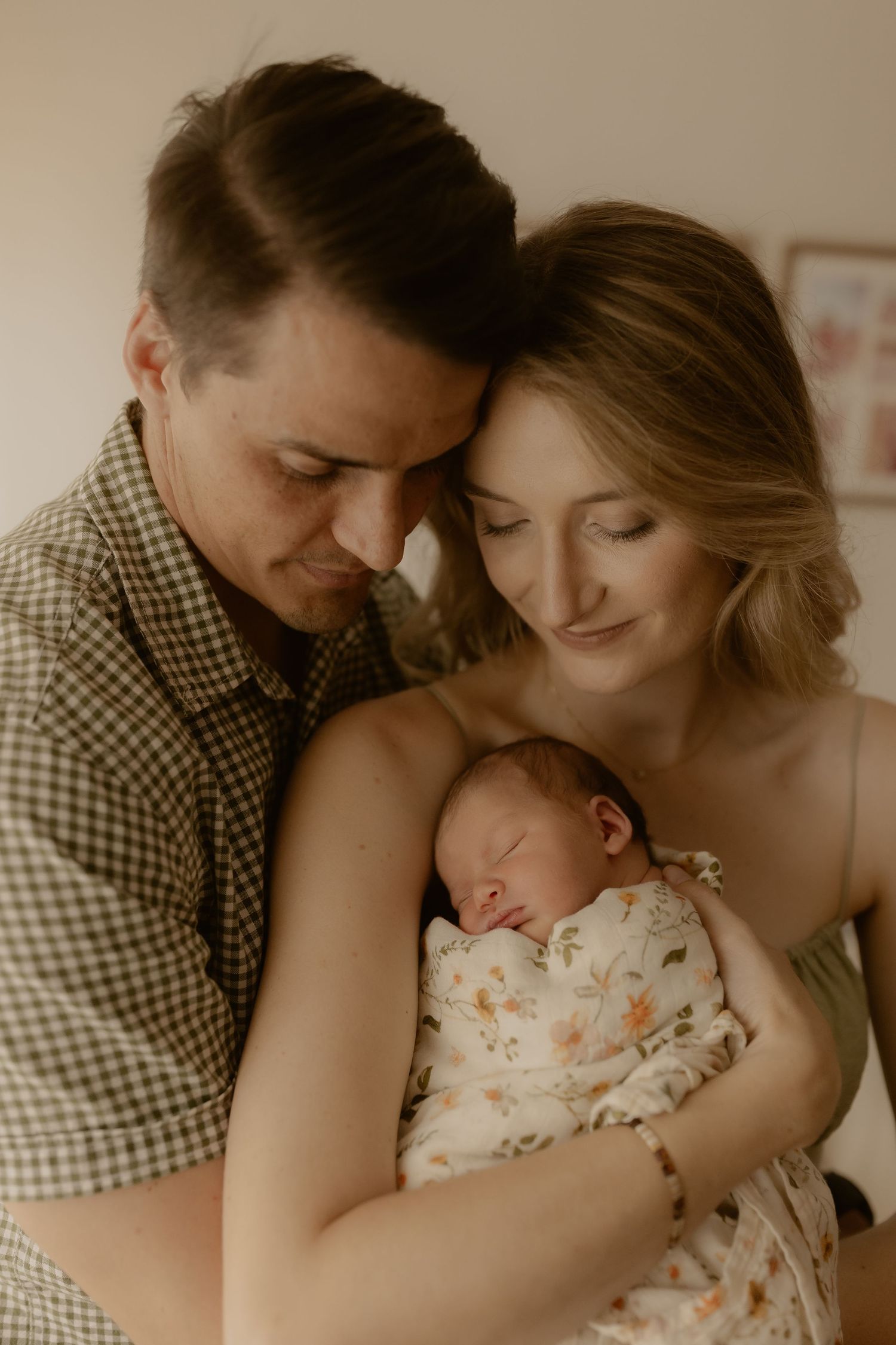 Intimate family moment with newborn in warm sepia tones.