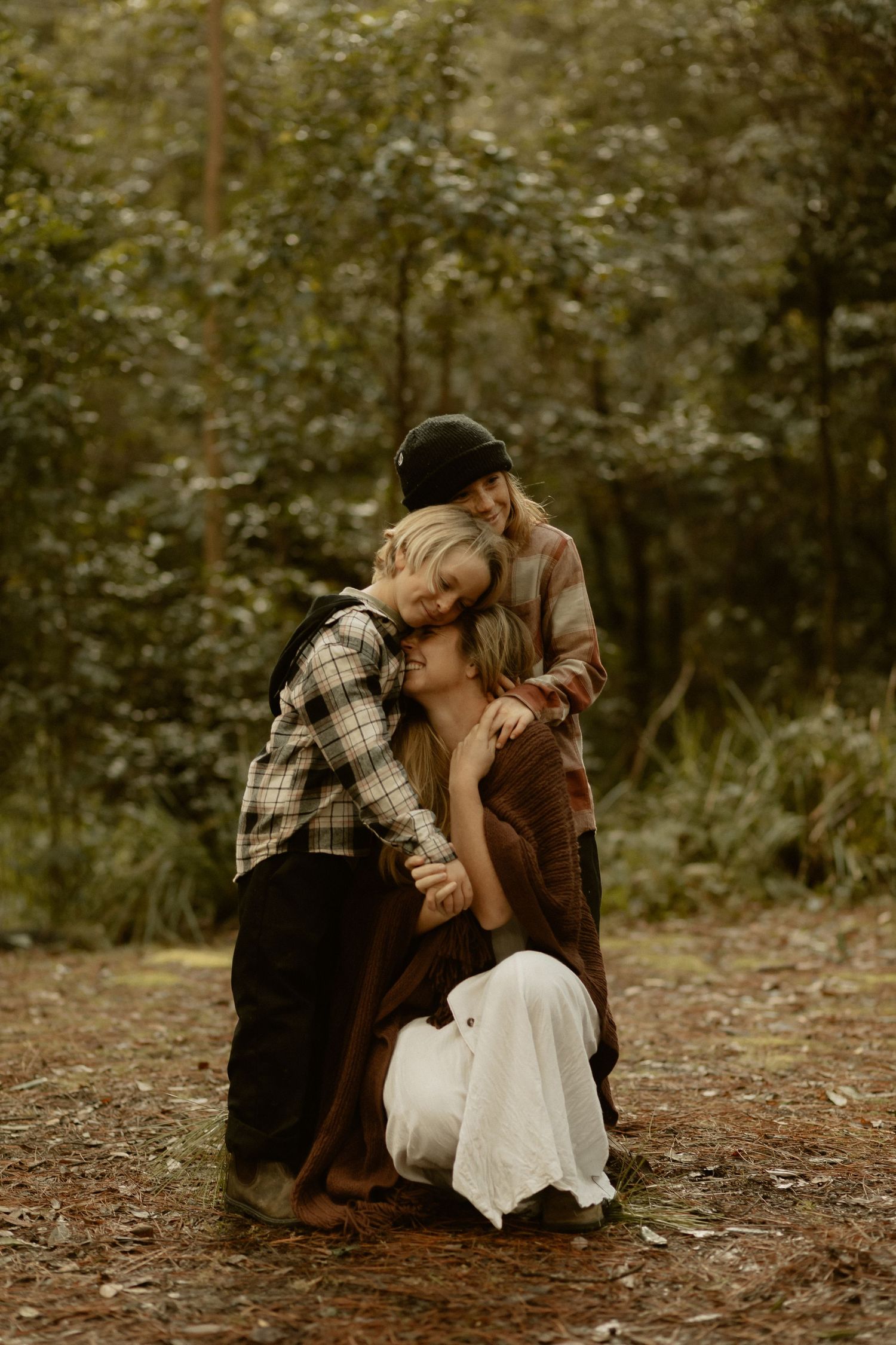 An emotional moment captured in sepia tones between two people sitting on forest ground.