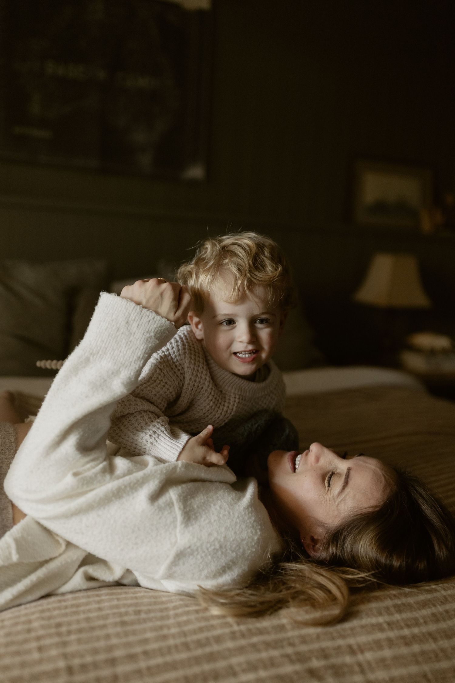 Heartwarming playtime moment captured in a dimly lit bedroom with cozy bedding.
