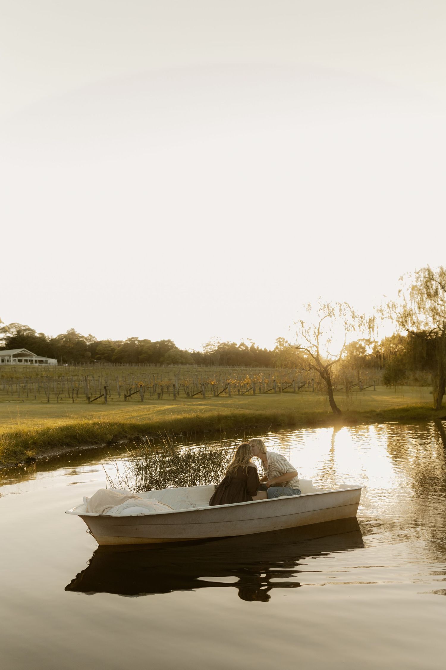Silhouette of boat gliding across peaceful lake waters in golden evening light.
