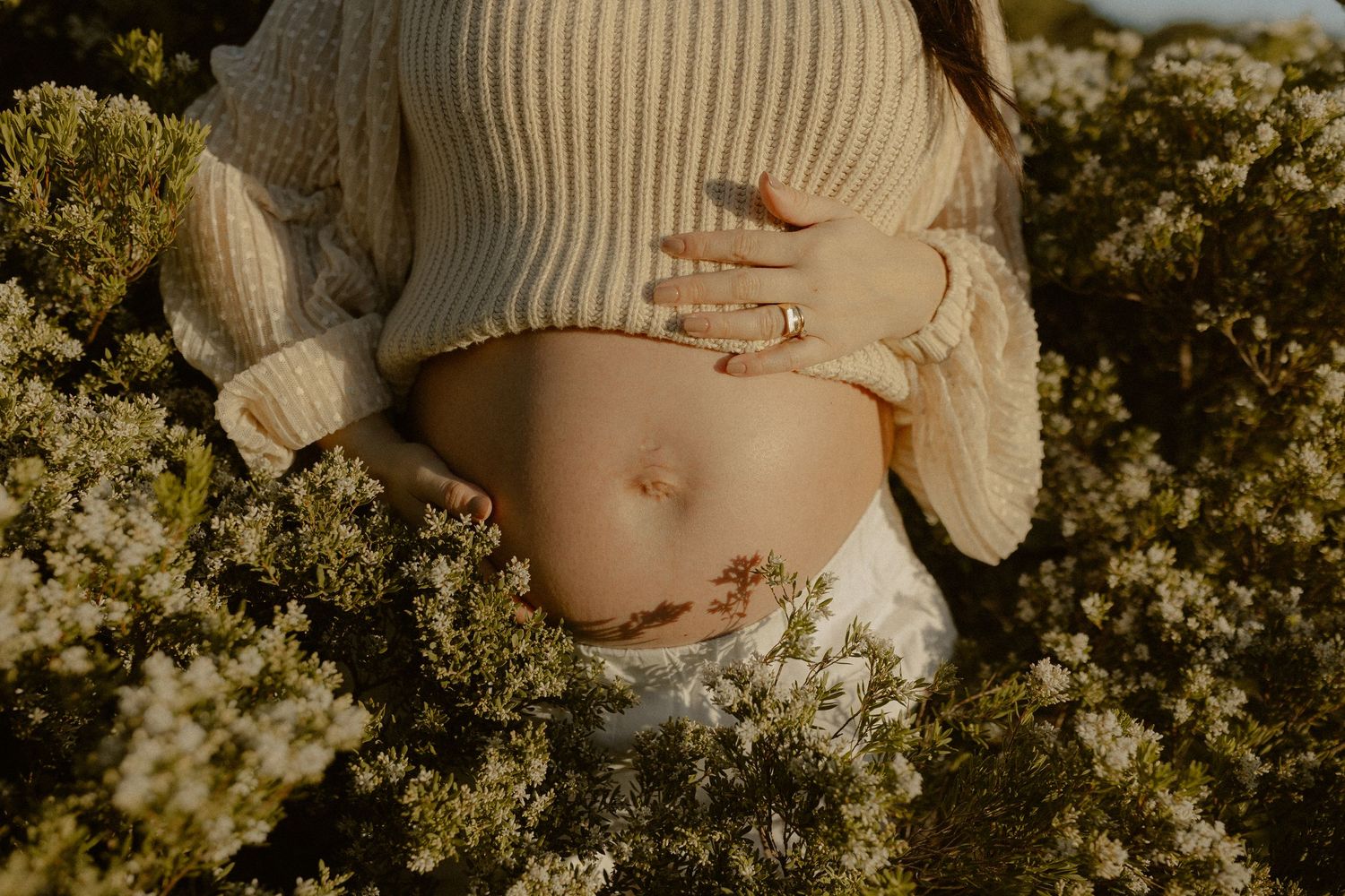A series of cropped maternity photos showing a pregnant belly in a cream sweater against a backdrop of autumn foliage.