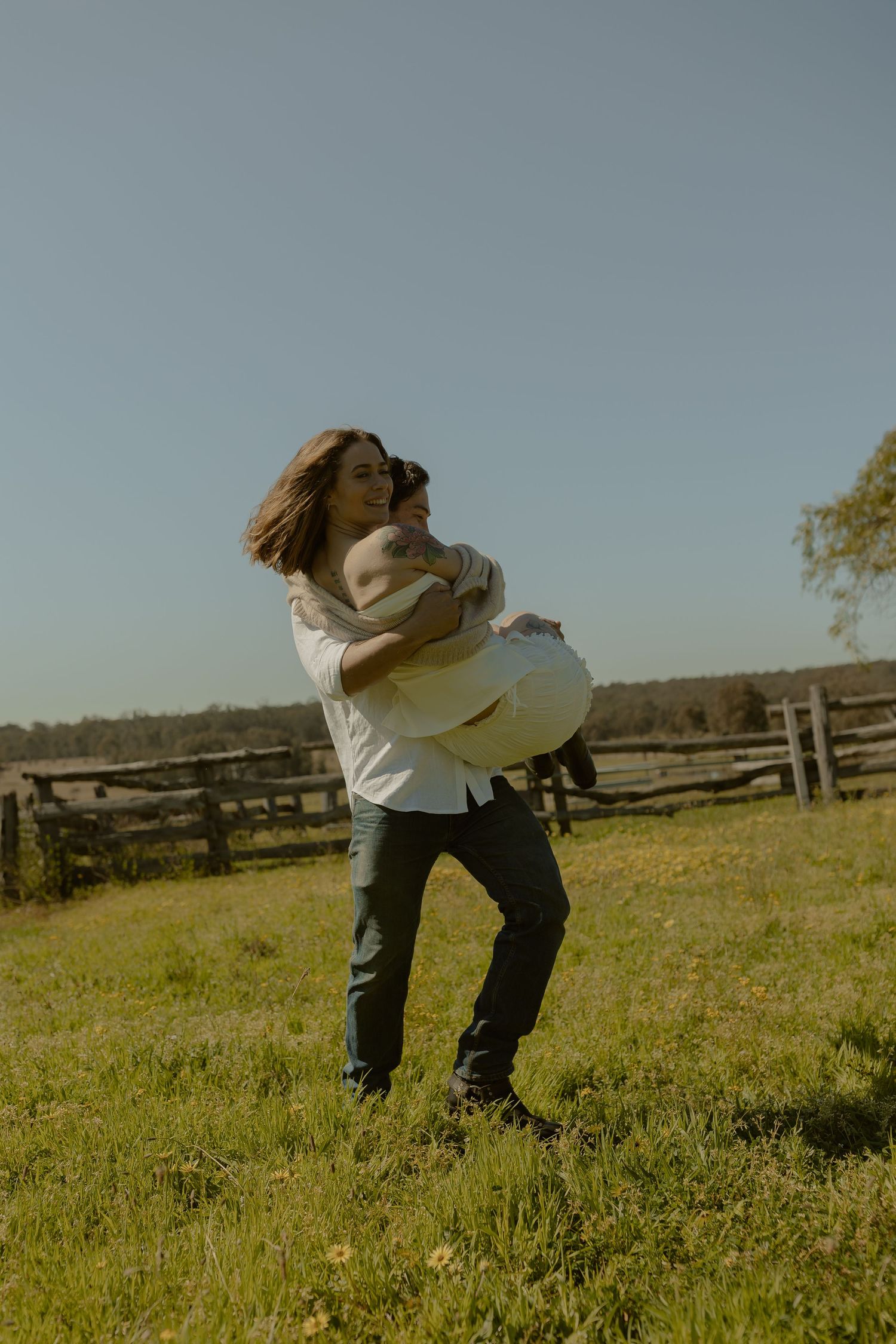 Playful dance moves in a sunlit field with rustic fencing.