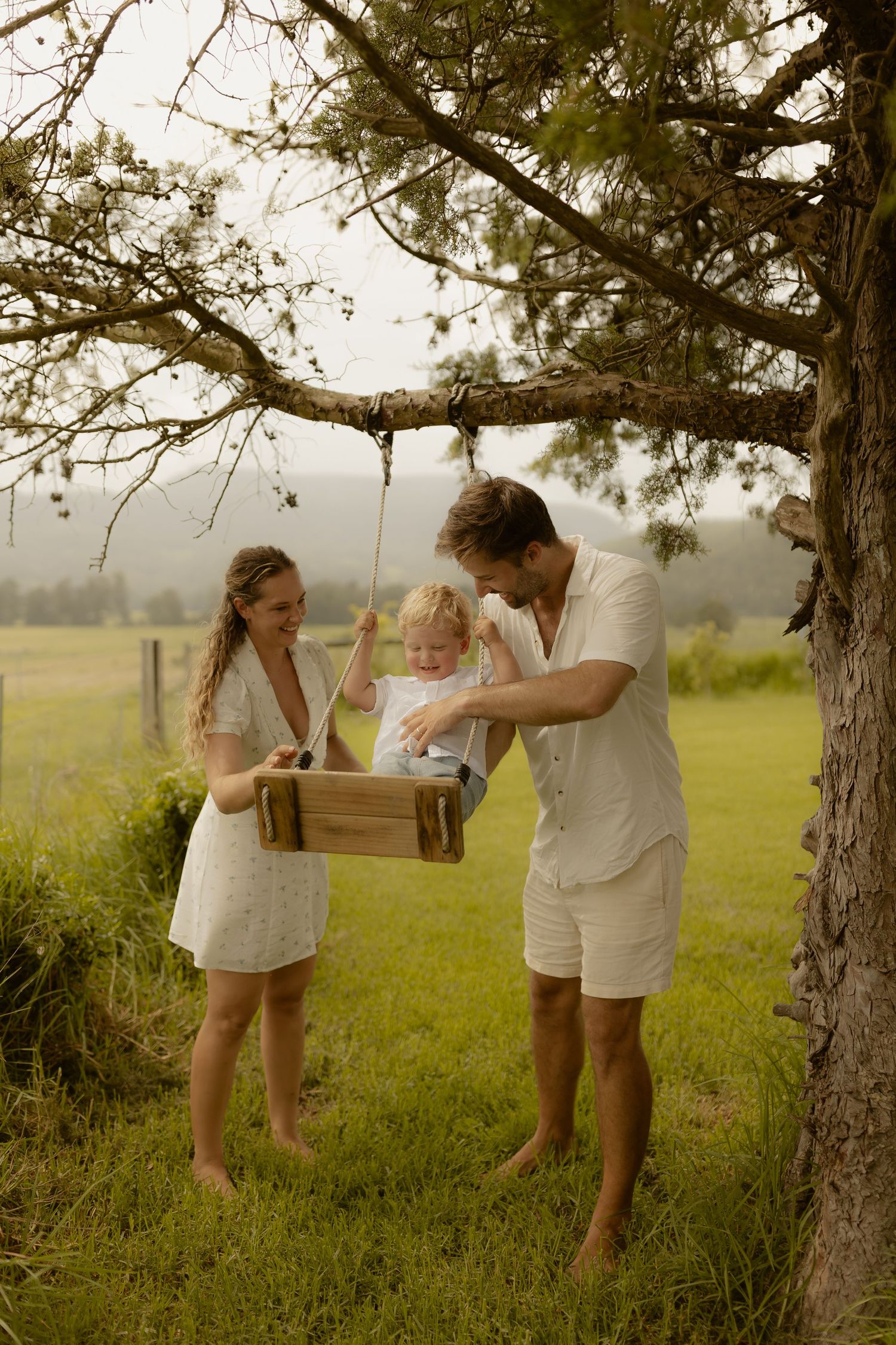 A series of candid moments showing people in white outfits playing near trees in a rural setting.