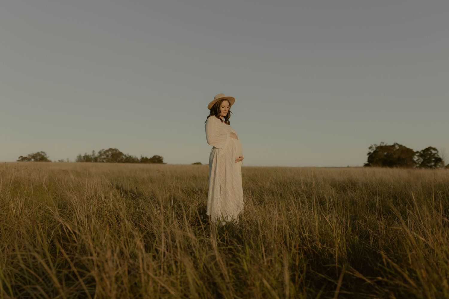 A couple dances together in a golden field at sunset, creating a romantic silhouette against the horizon.