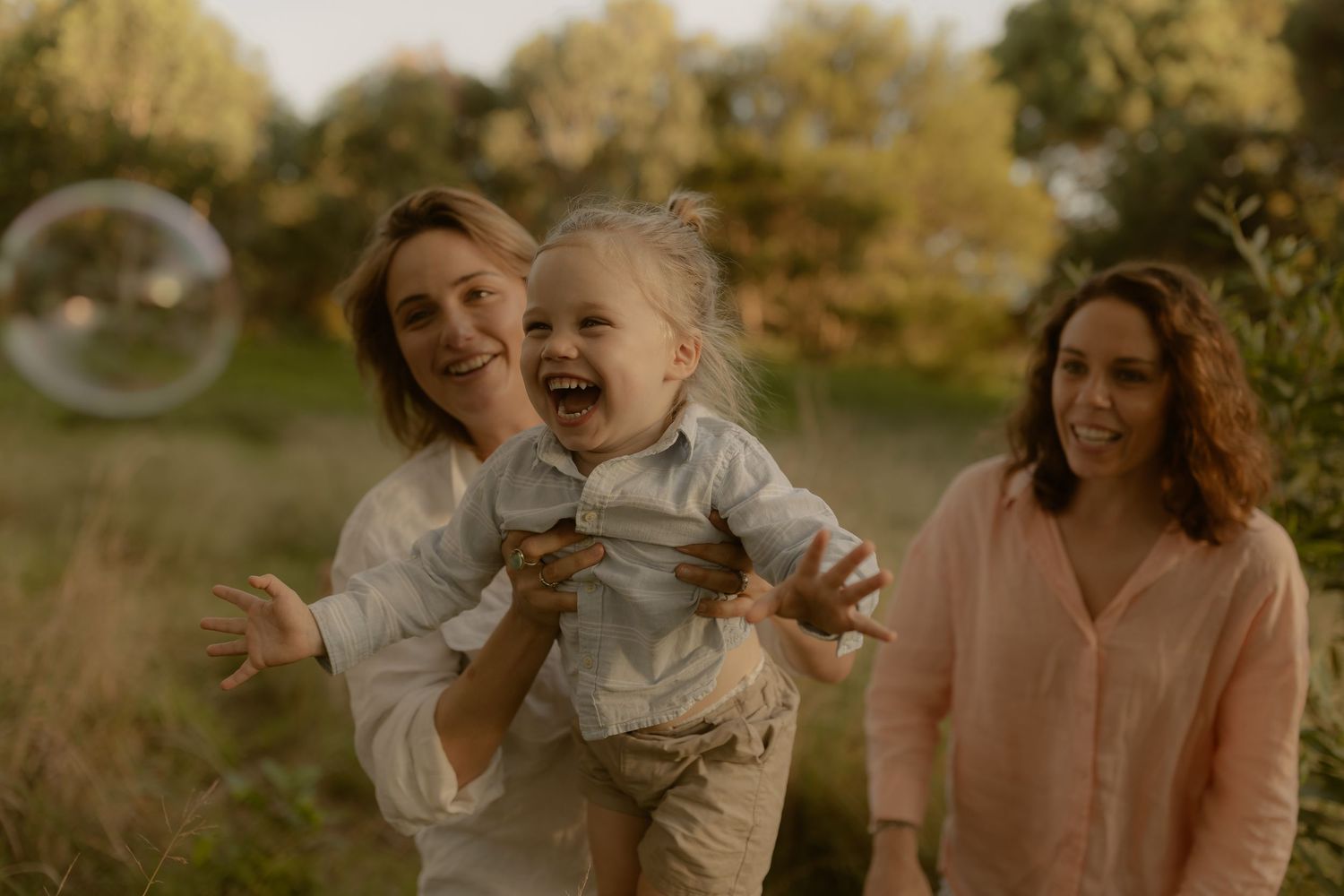 Family enjoying a playful moment together outdoors during golden hour sunset.