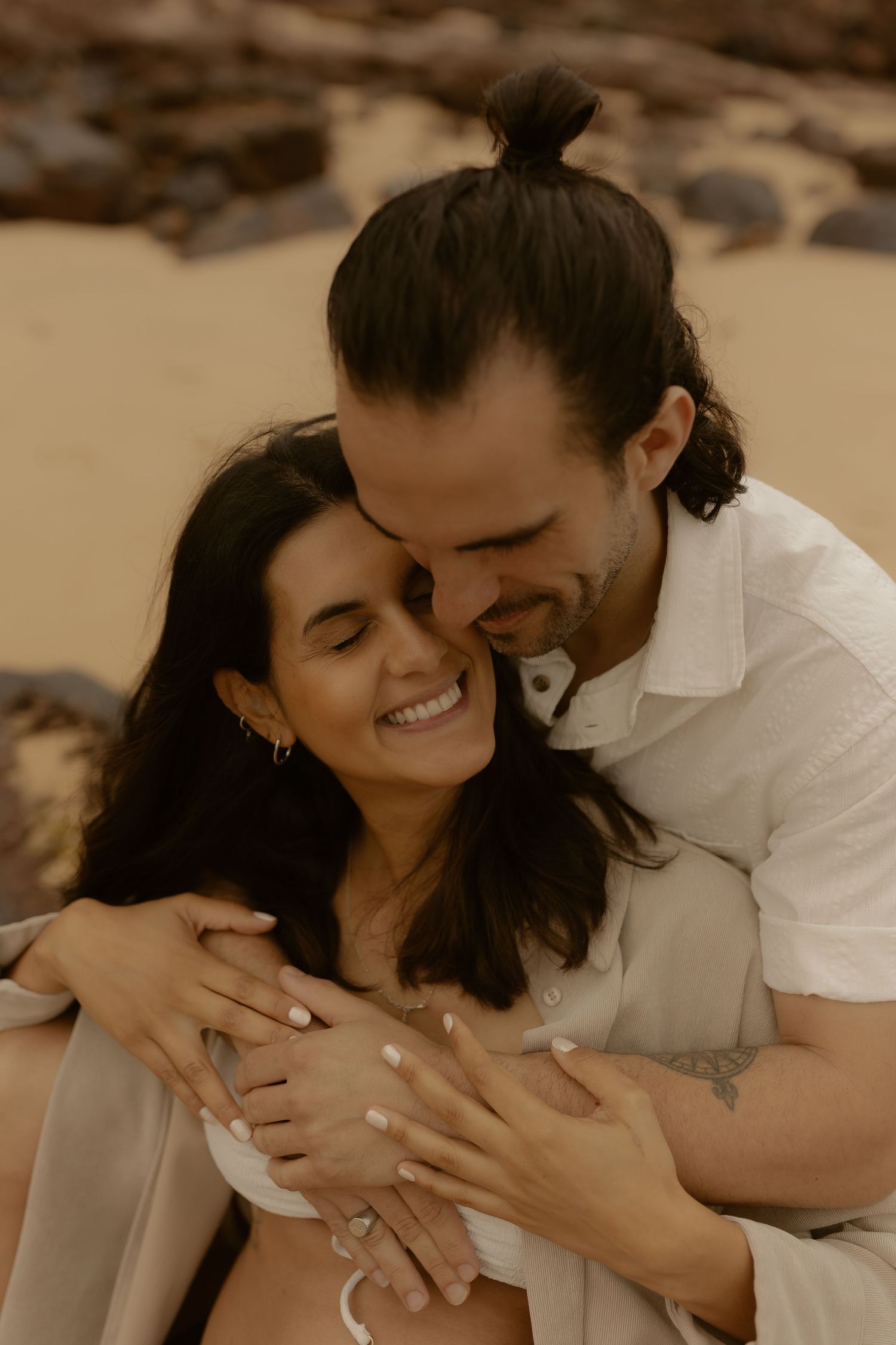 A loving couple shares an intimate moment while embracing on a beach.