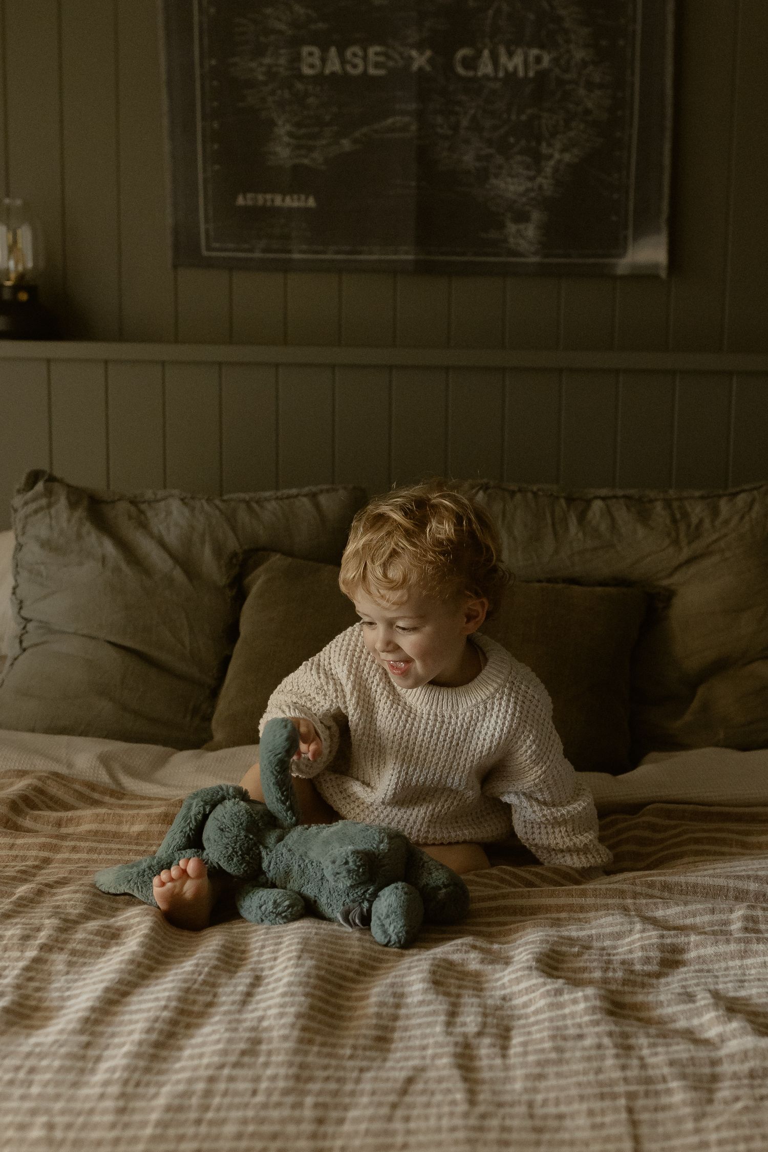 Cozy indoor scene with someone lounging on a bed next to a stuffed animal beneath wall decorations.
