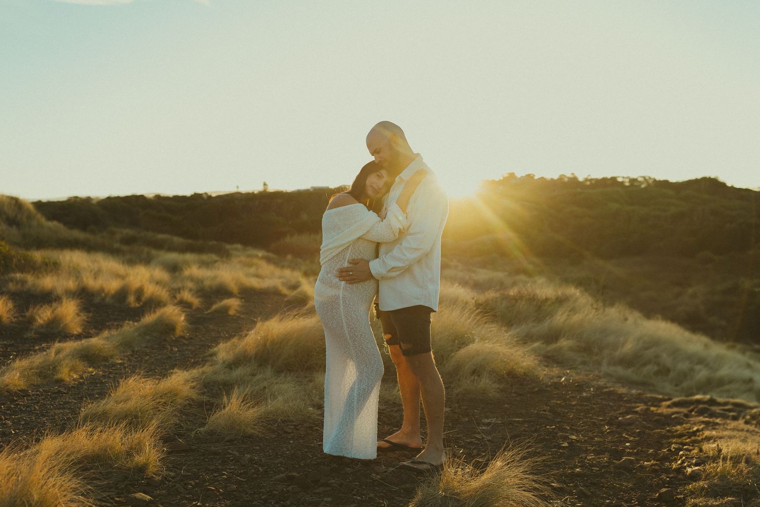 Romantic silhouettes embrace against a glowing sunset backdrop in nature.