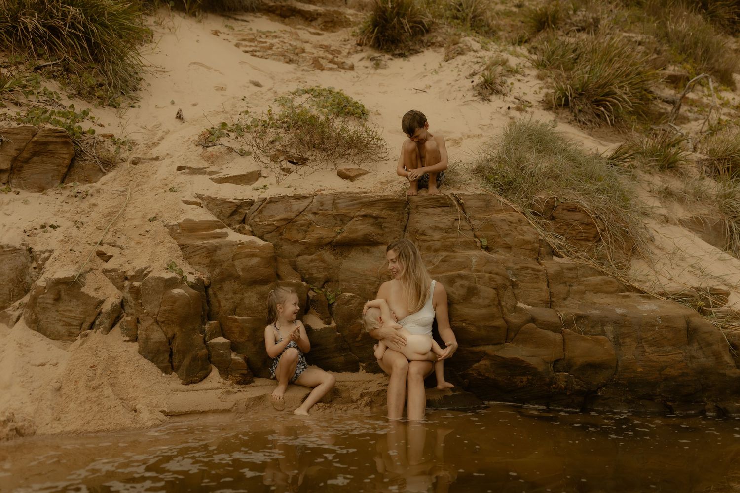 Family enjoying time together on rocky beach area during golden hour.