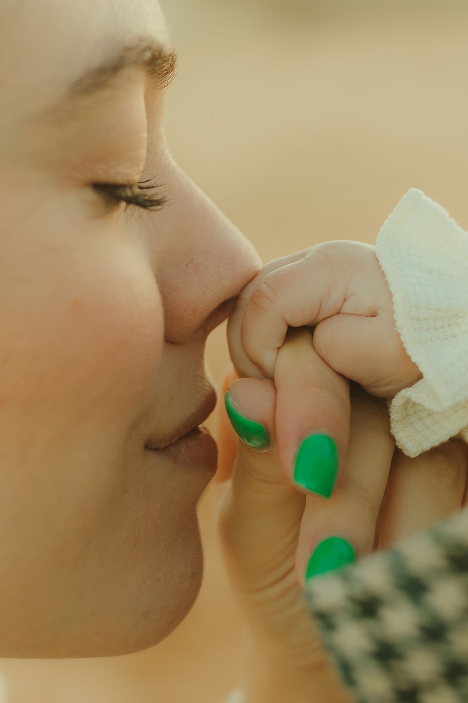 A close-up view of someone kissing a small hand while wearing bright green nail polish.