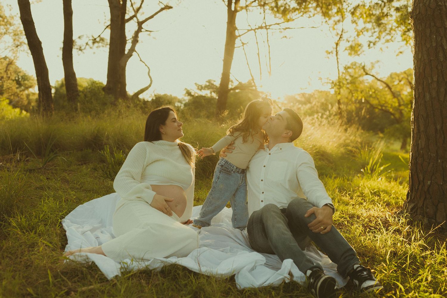 A tranquil family gathering on a white blanket in a sunlit meadow.